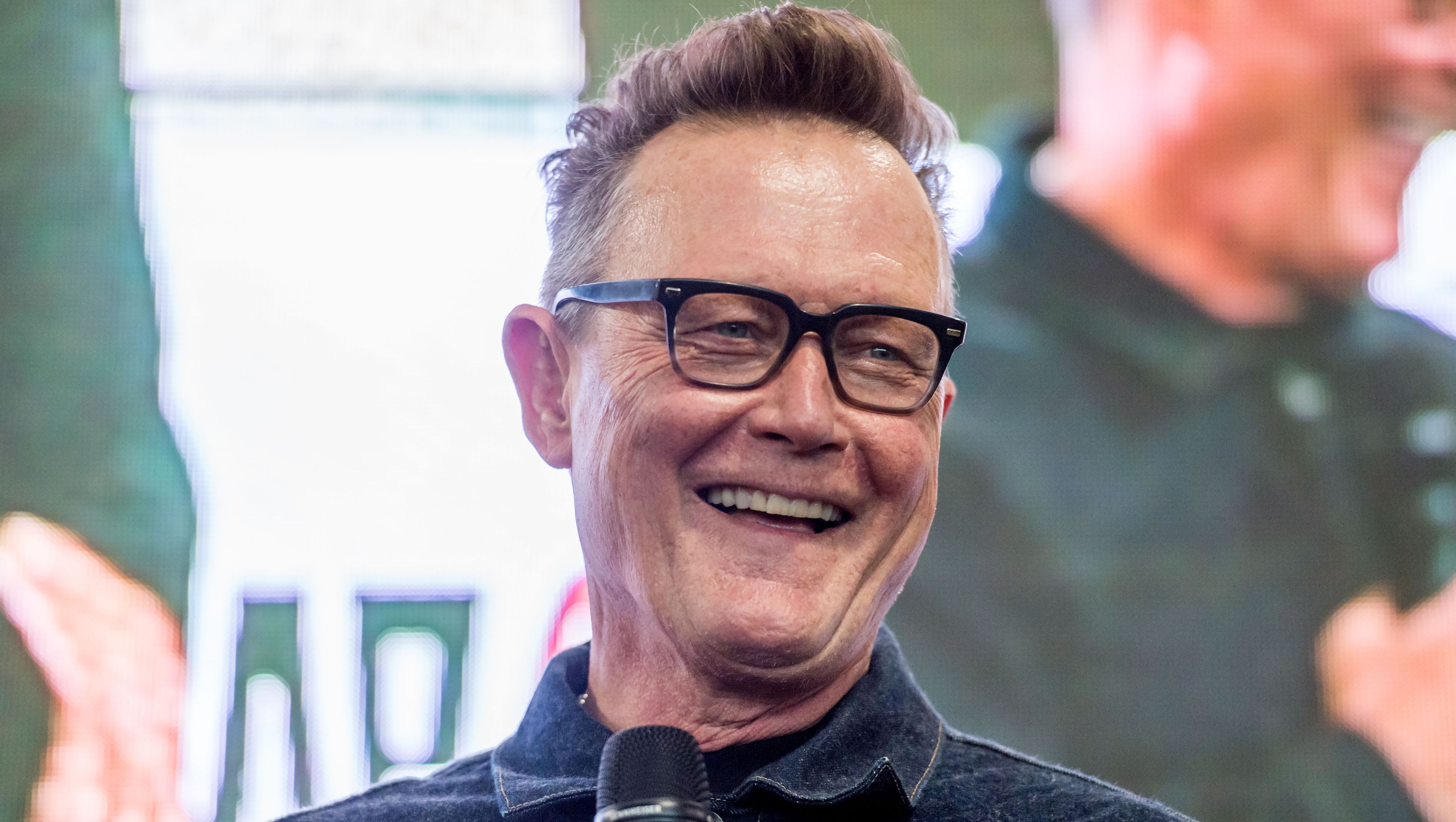 Robert Patrick smiles in glasses and a collared shirt.
