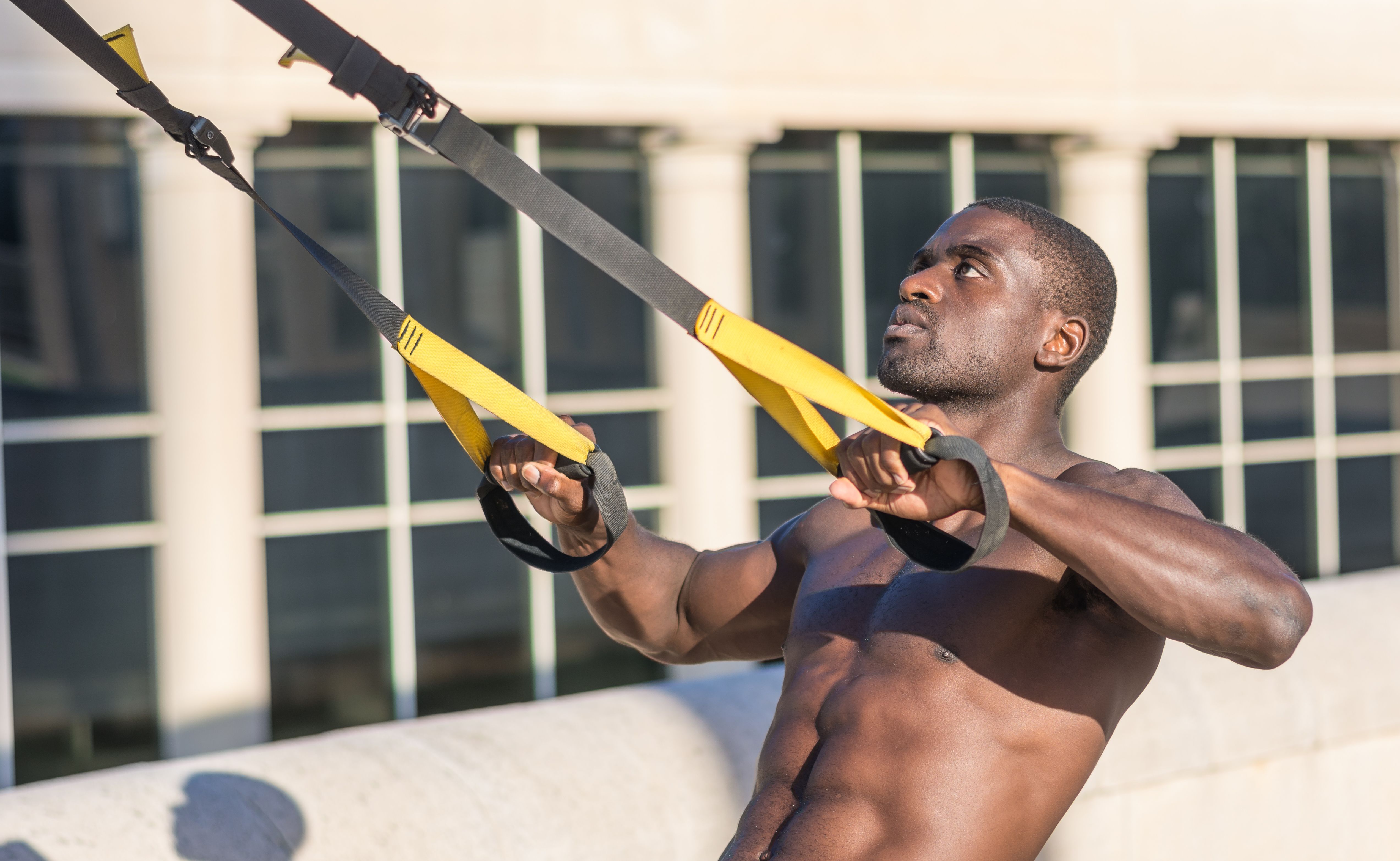 Young man using a TRX system outdoor.