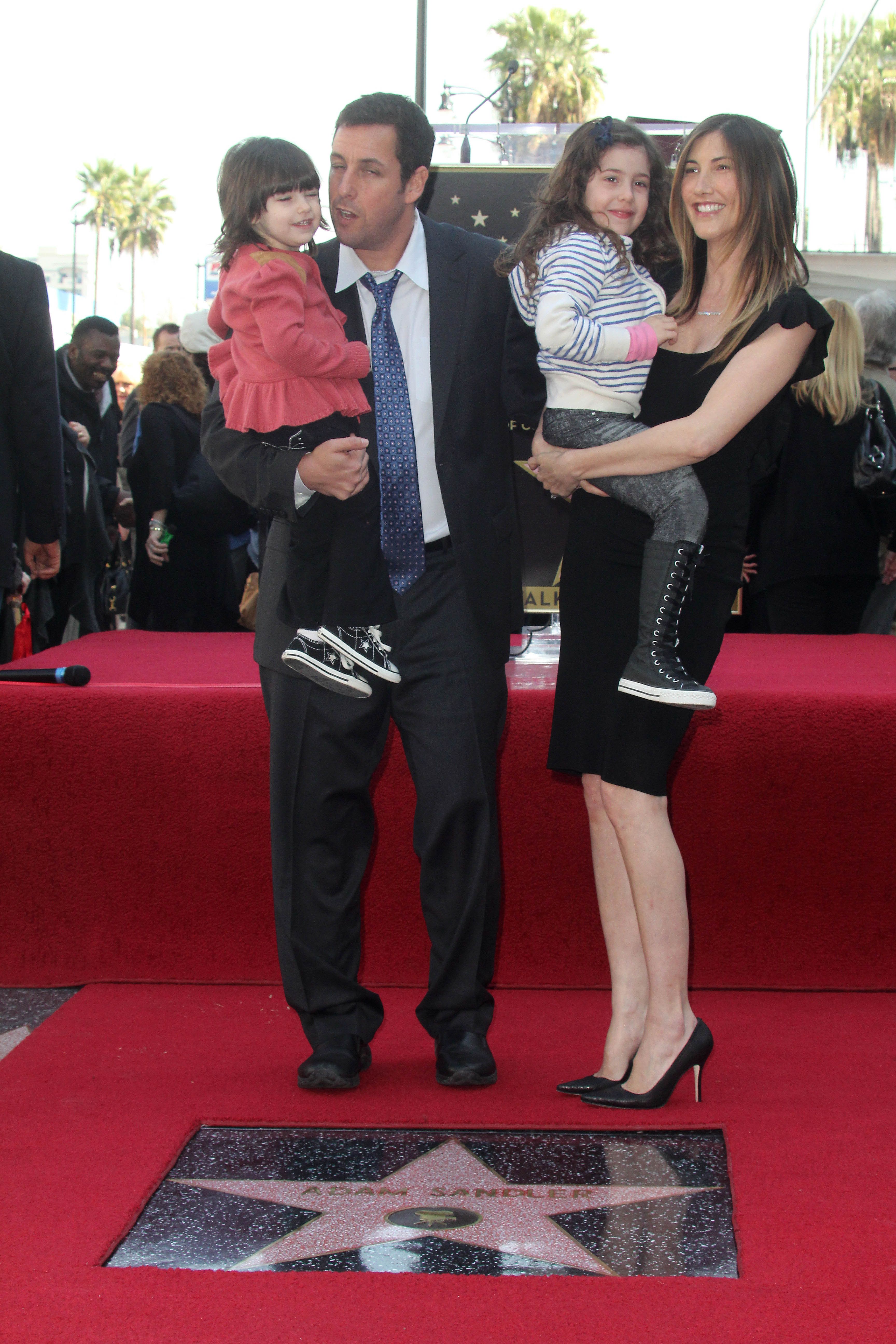 Adam and Jackie Sandler hold their two kids, Sunny and Sadie at his Walk of Fame star.