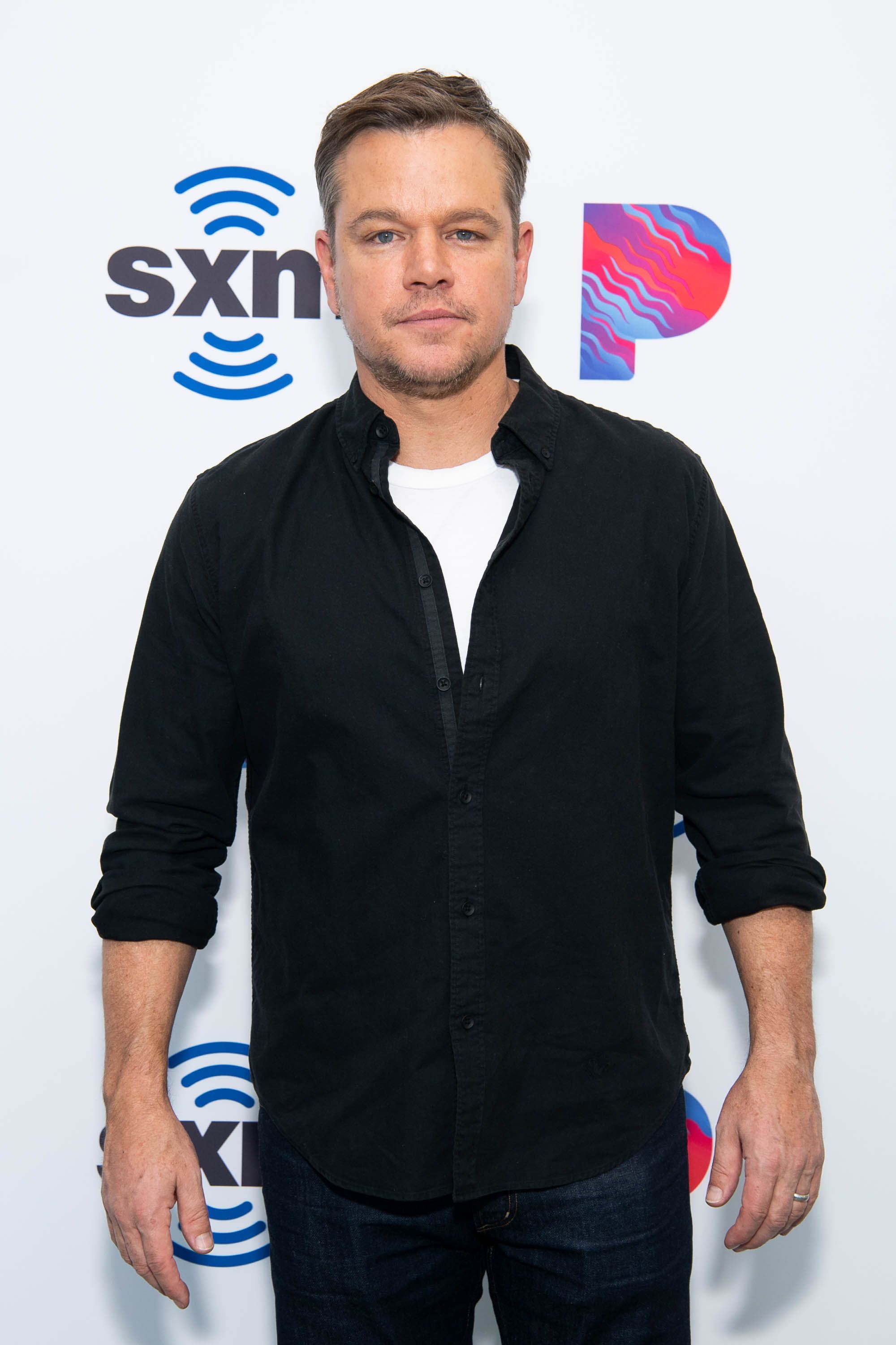 Matt Damon wears a white T-shirt under a black button-down.