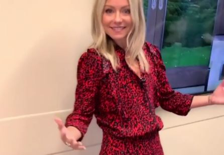 Kelly Ripa poses smiling backstage in a dress