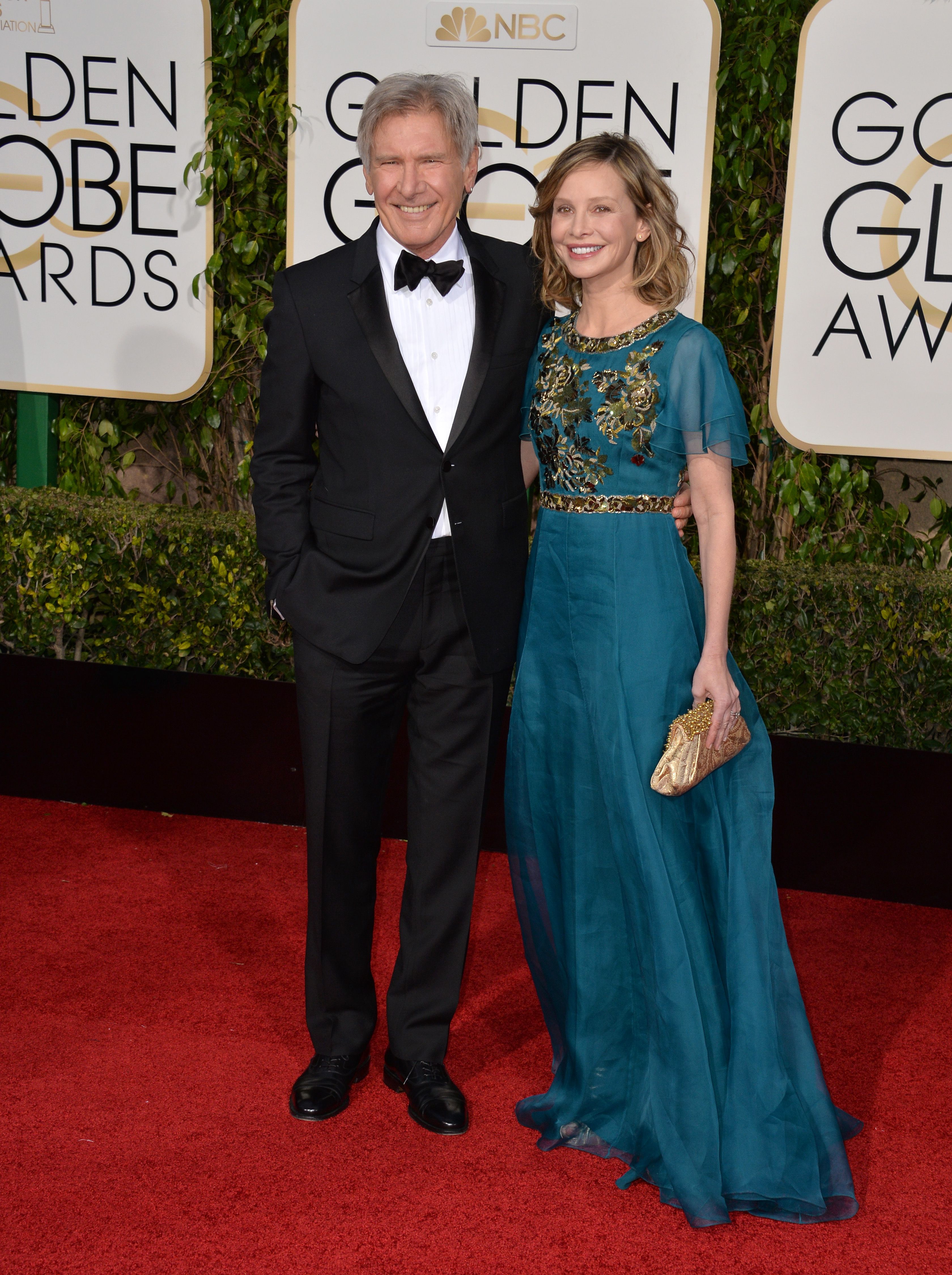 Calista Flockhart smiles with a teal gown with smiling Harrison Ford.