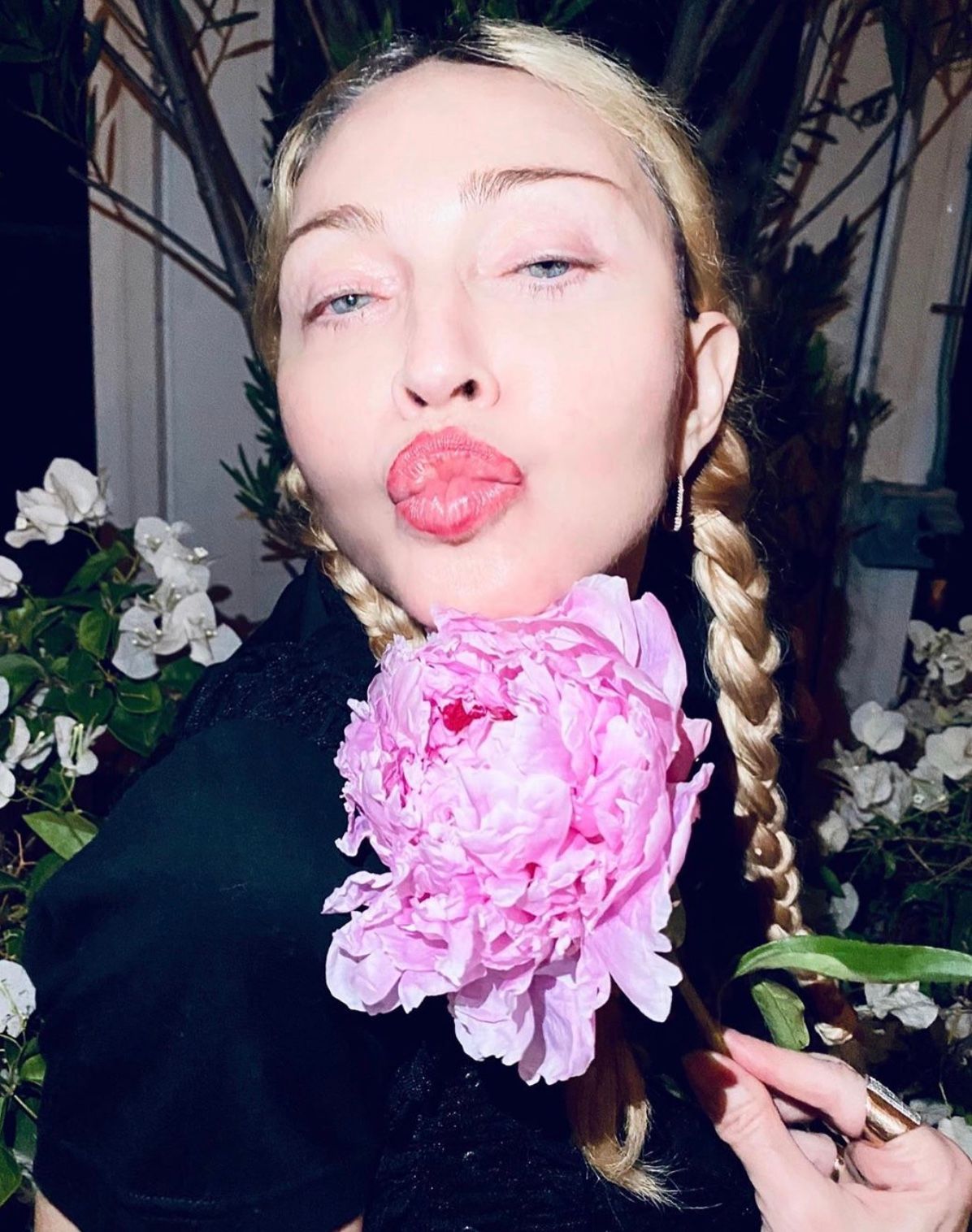 Madonna holds a flower and blows a kiss to the camera