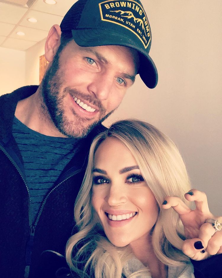 Carrie Underwood makes claw shape with hand beside Mike Fisher