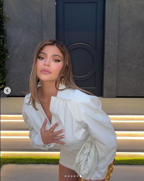 Kylie Jenner poses in a white shirt near steps