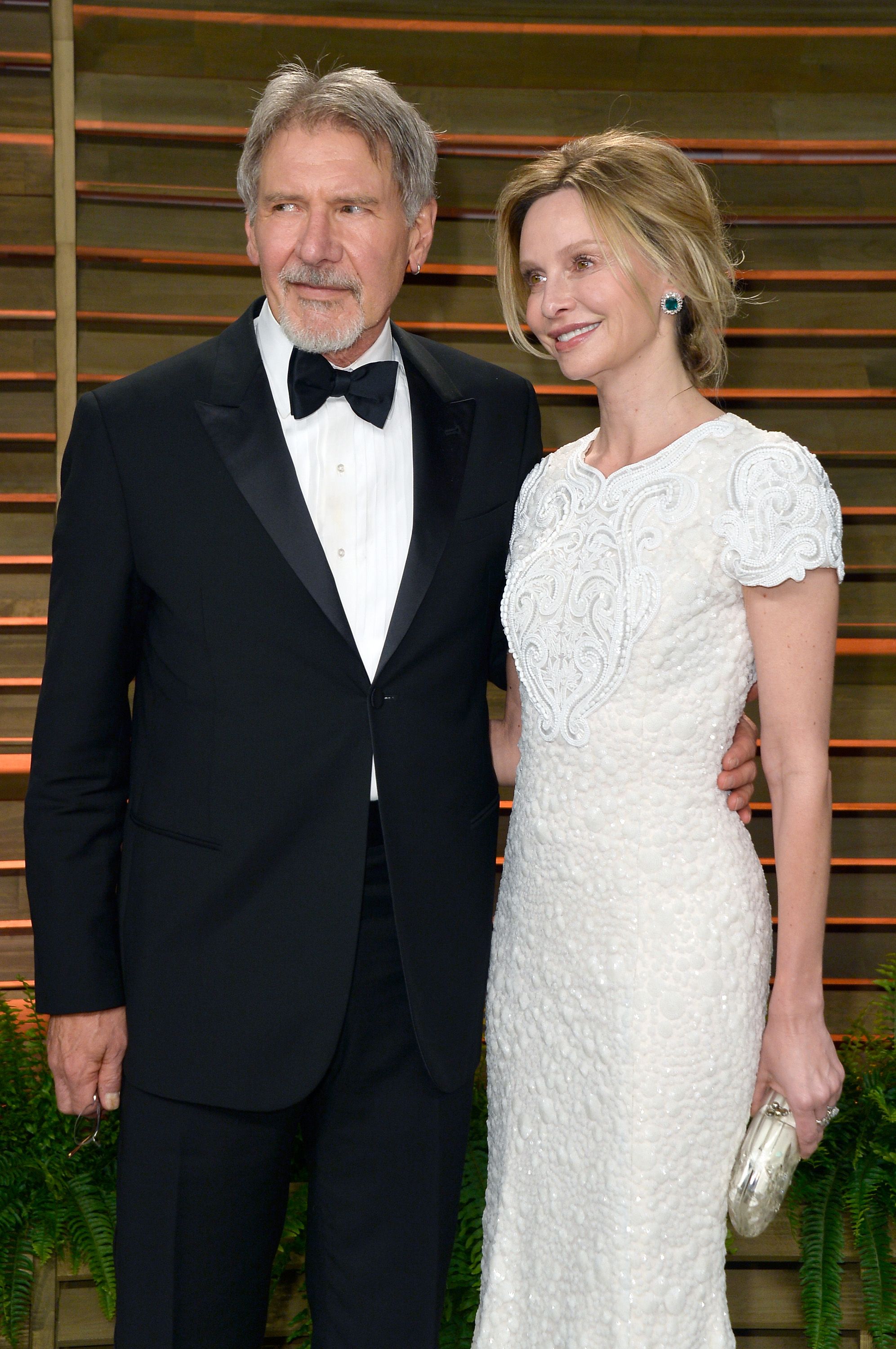 Harrison Ford holds wife Calista Flockhart in a white dress.
