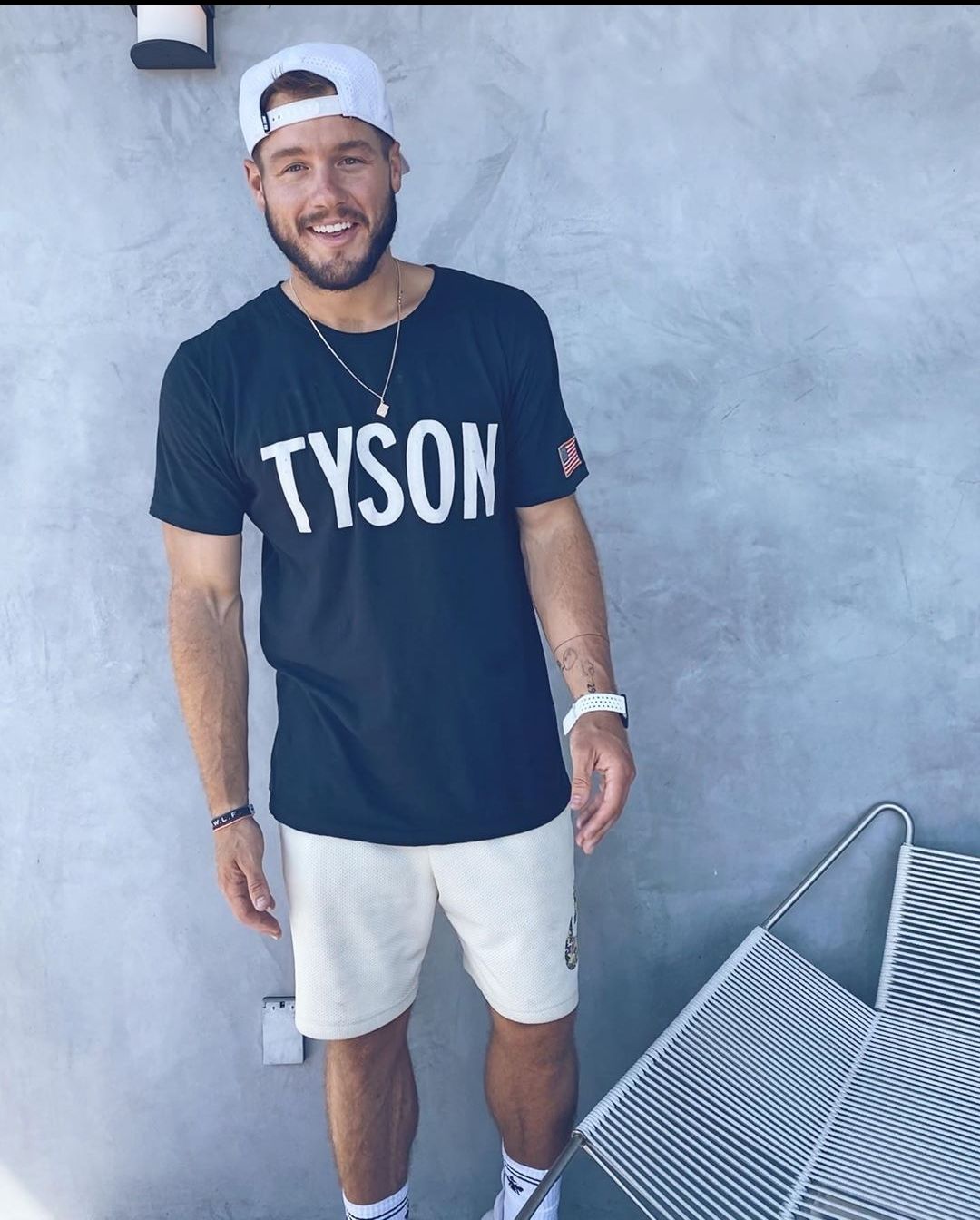 Colton Underwood looks amazing in casual shorts paired with a blue round neck shirt and cap, that's turned backwards. 