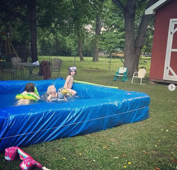 Children playing in a blue tarp lined hay bale pool