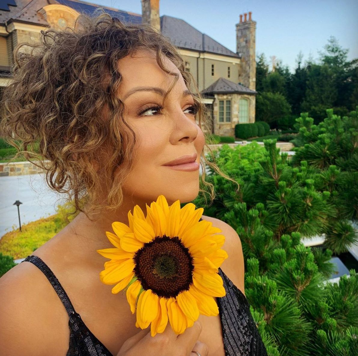 Mariah Carey at her estate holding a sunflower