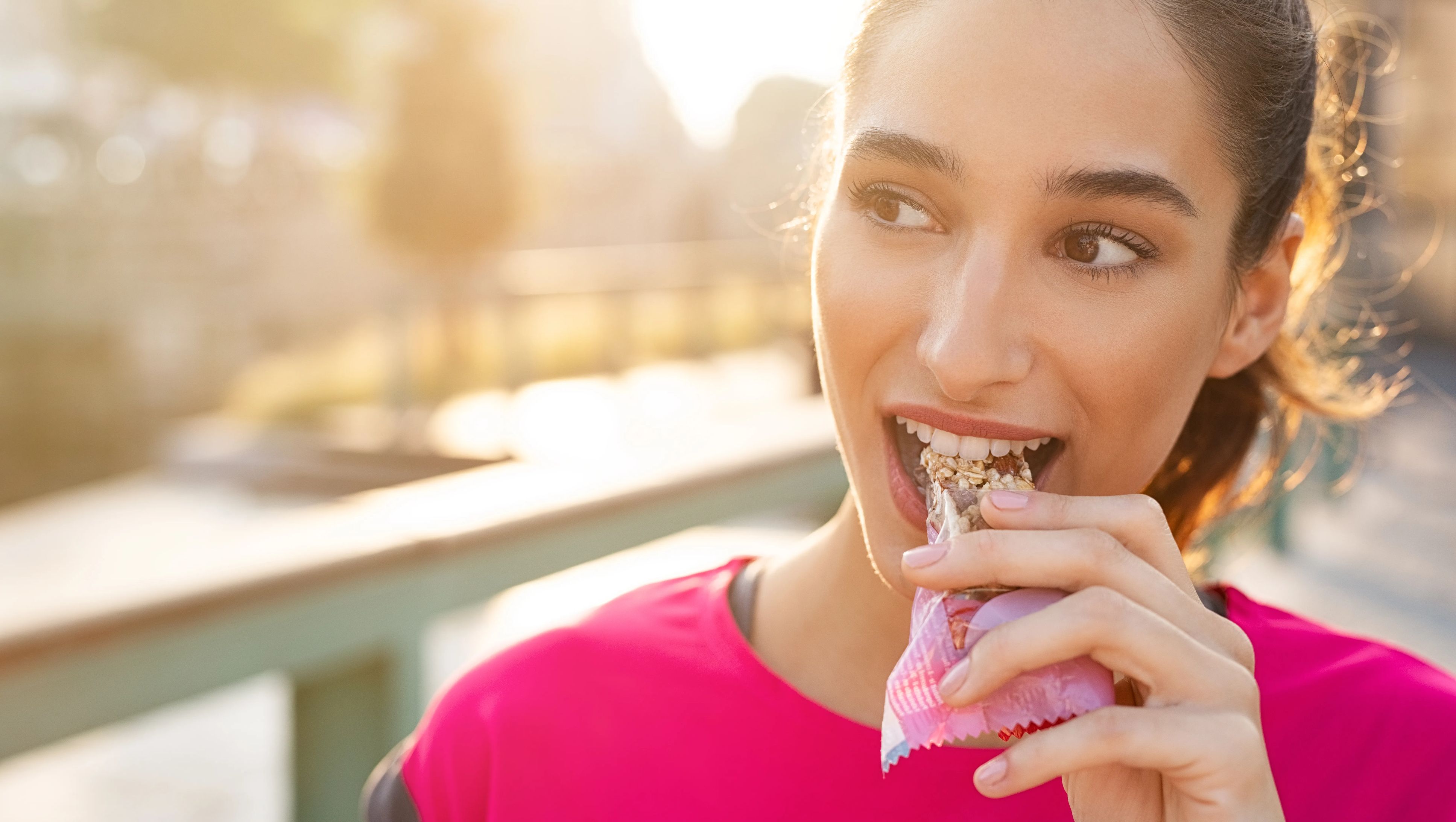 Young woman snacking on a cereal protein bar. 
