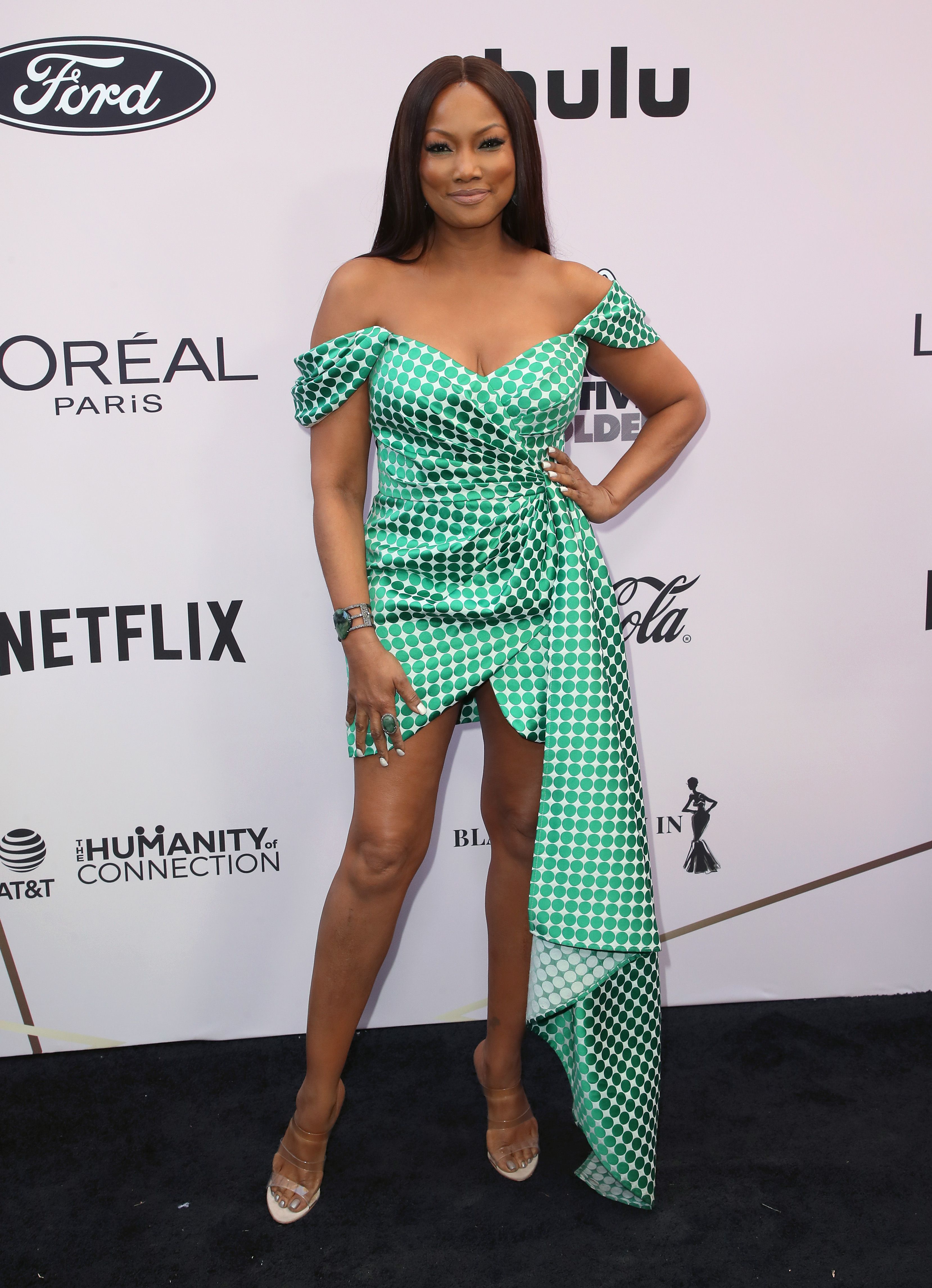 Garcelle Beauvais wears a green and white printed off-the-shoulder gown.