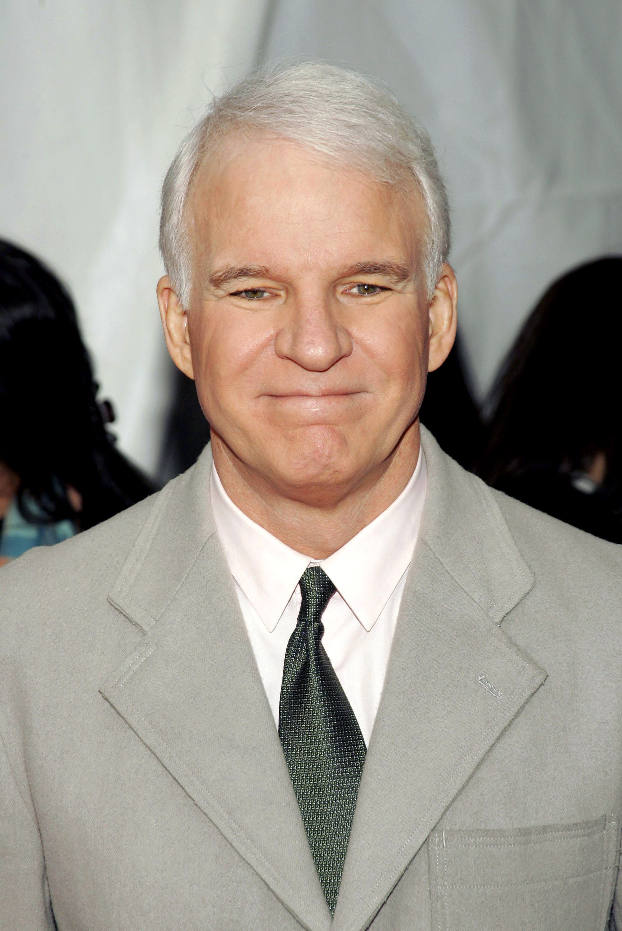 Steve Martin wears a gray suit and tie.