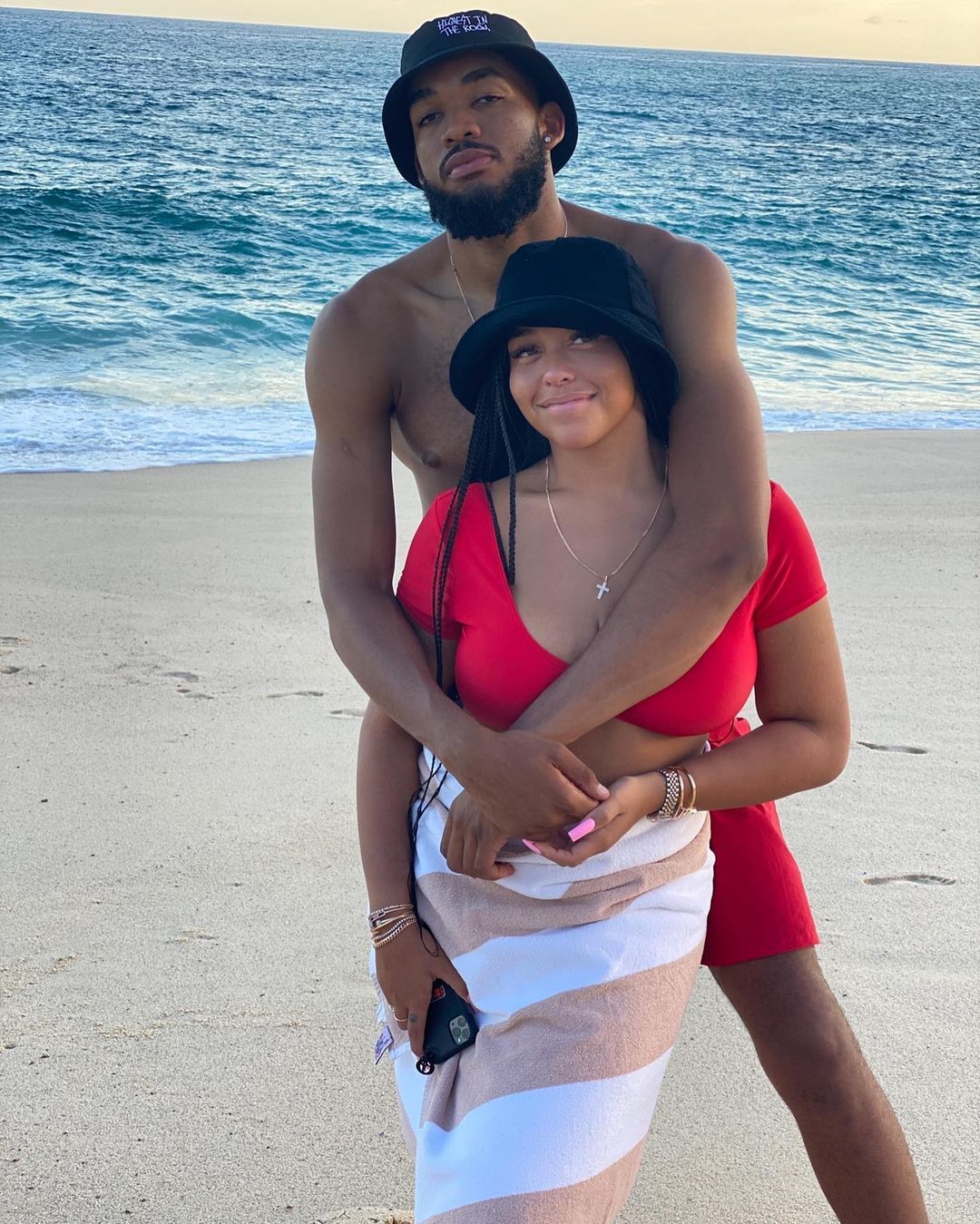 Jordyn Woods and Karl Anthony-Towns hug on a beach.