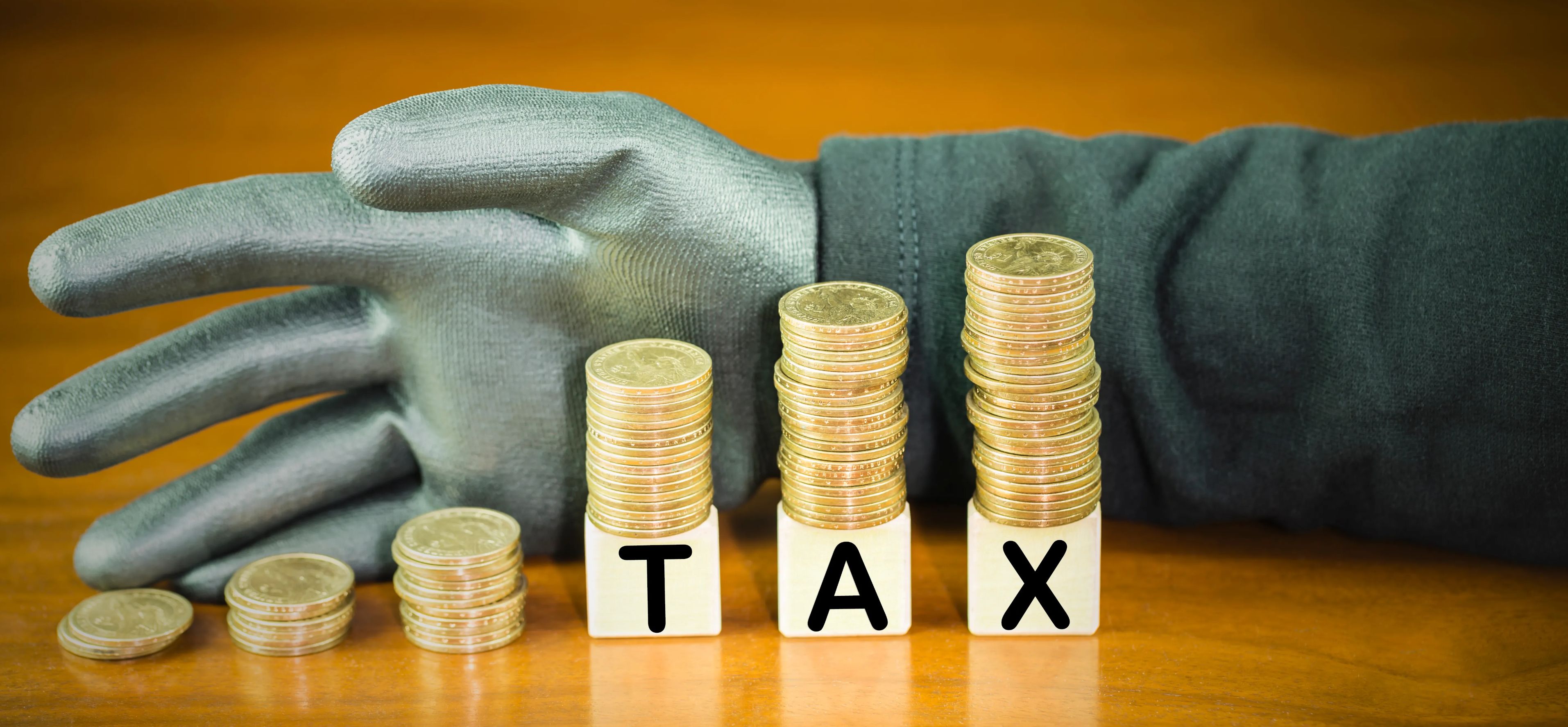 Hand behind coins with the word "tax" stock photo