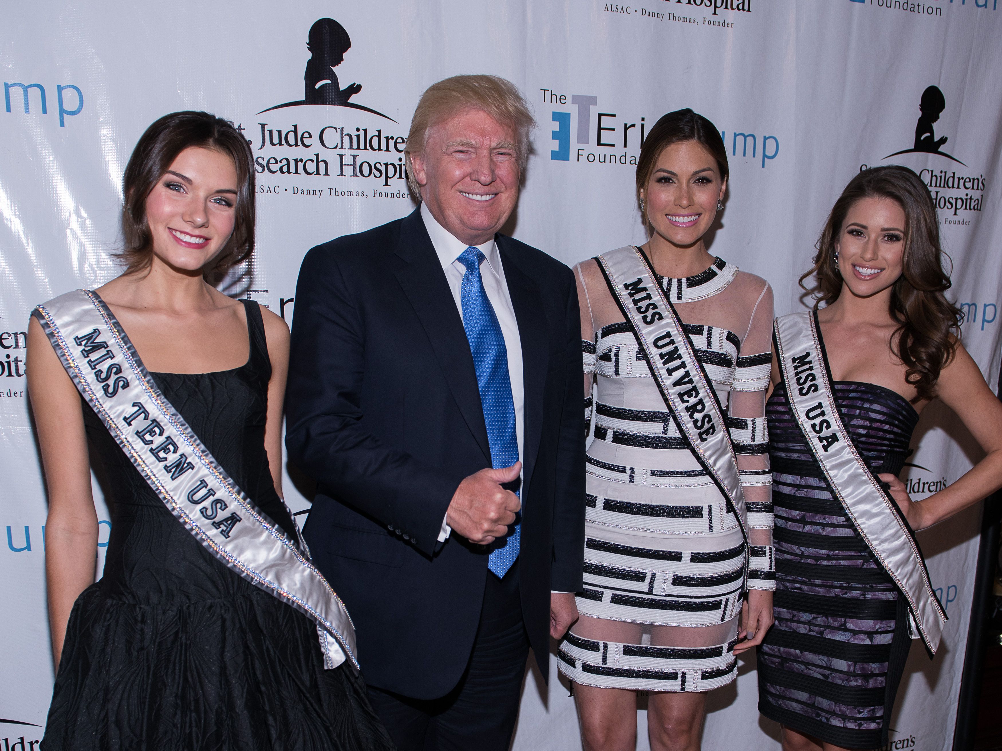 Donald Trump gives thumbs up while posing with beauty pageant winners. 