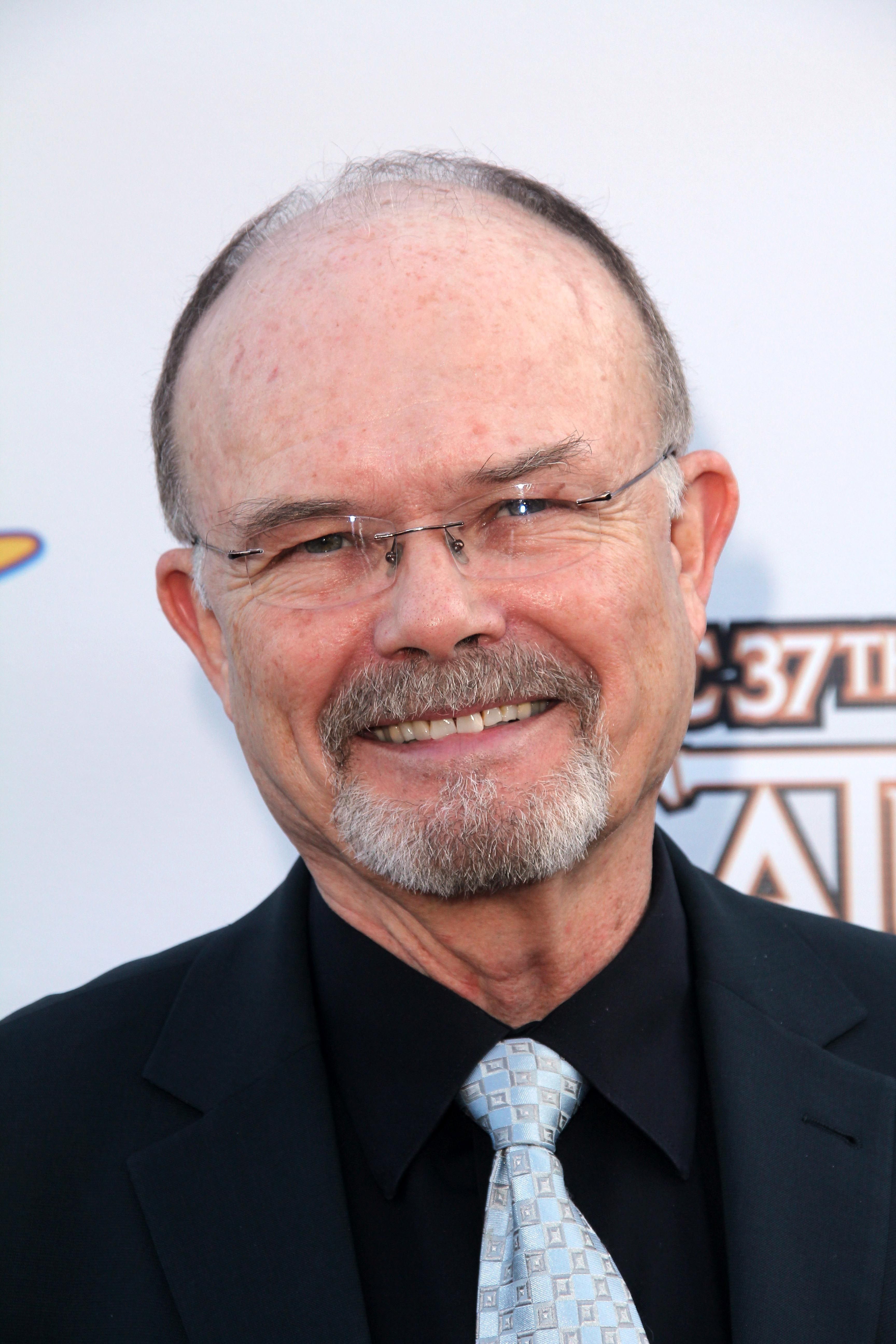Kurtwood Smith smiles in a black shirt and light blue tie.