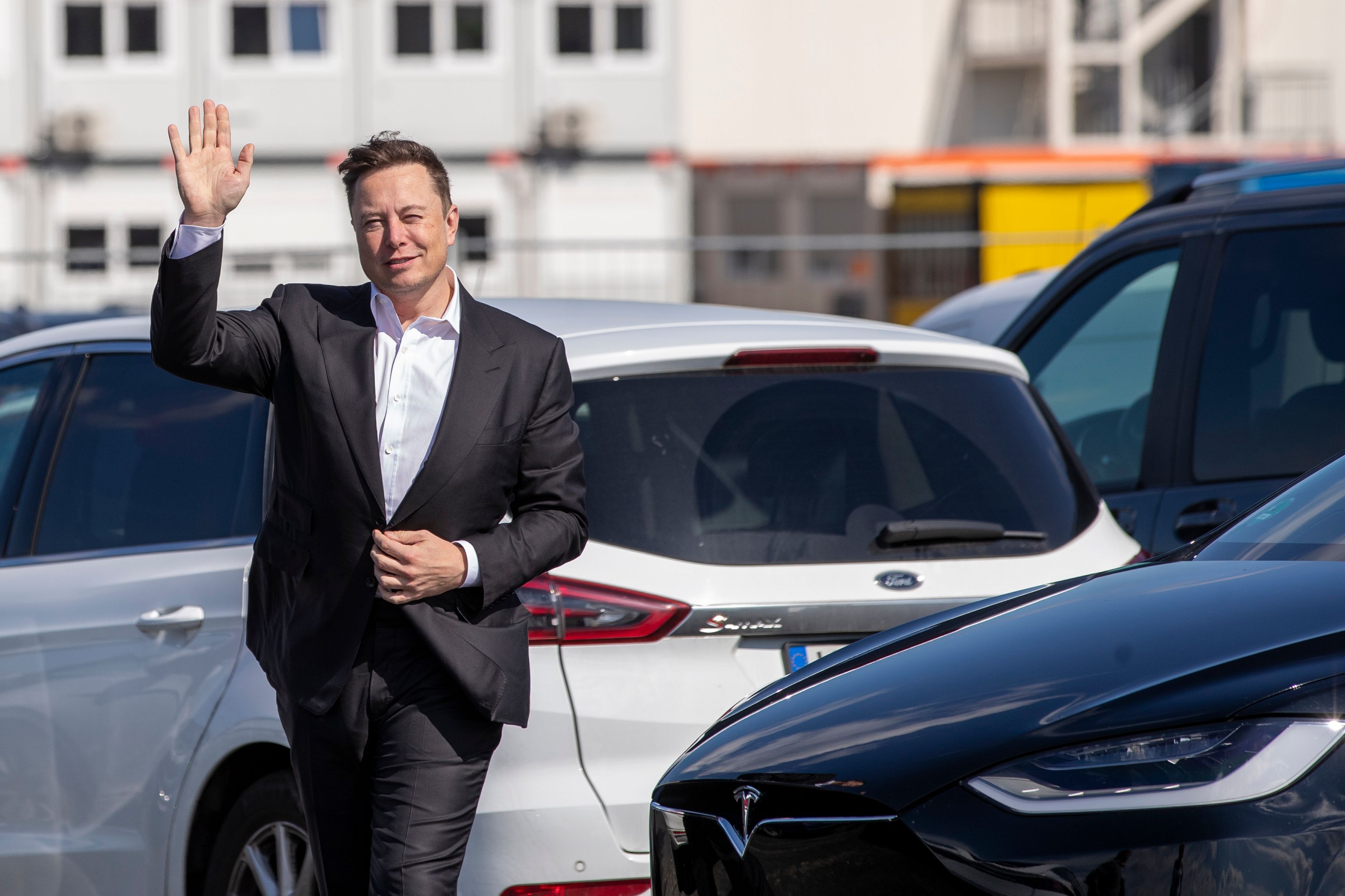 Elon Musk waves at photographers.