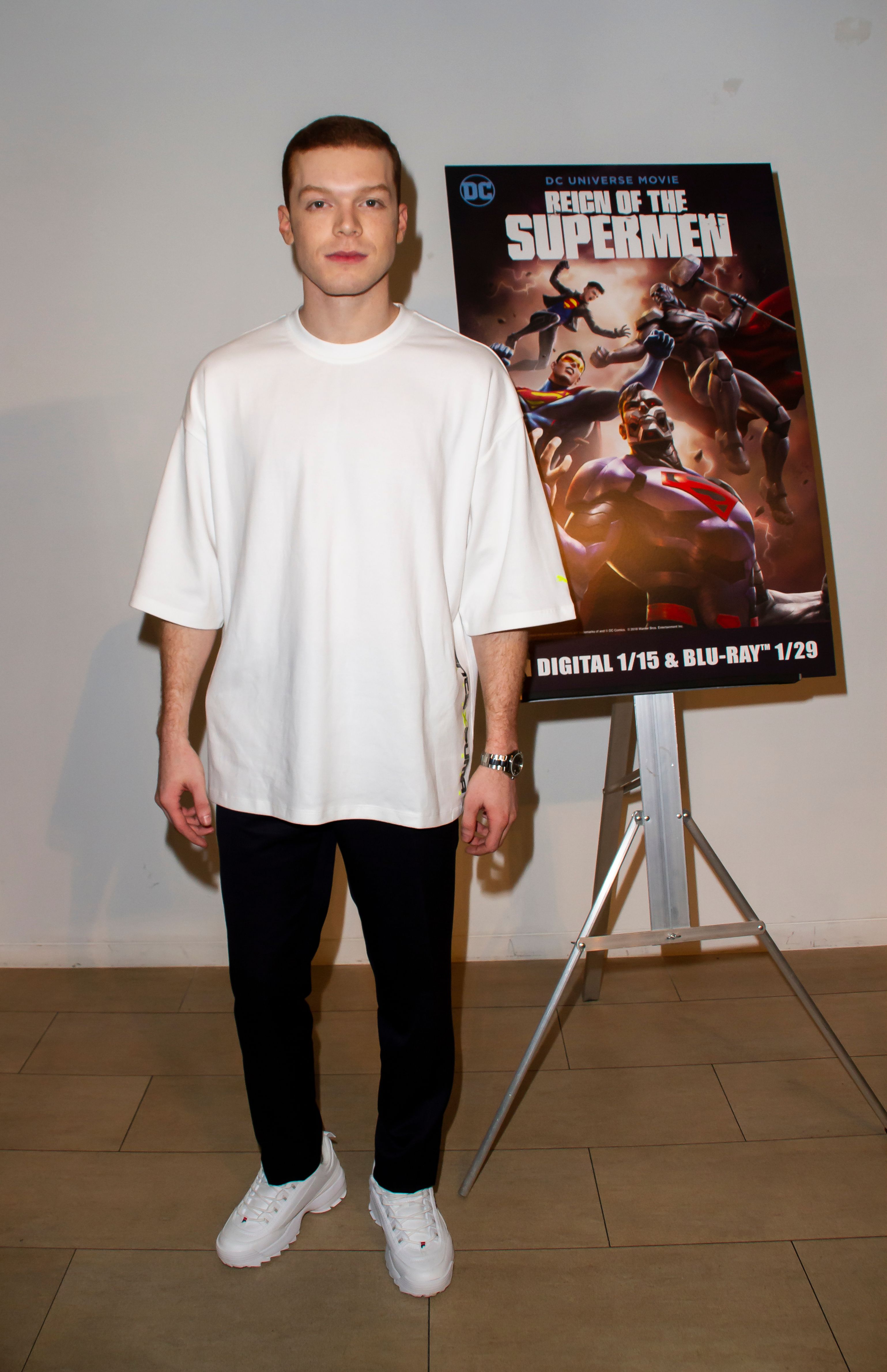 Cameron Monaghan wears a white T-shirt and tennis shoes.