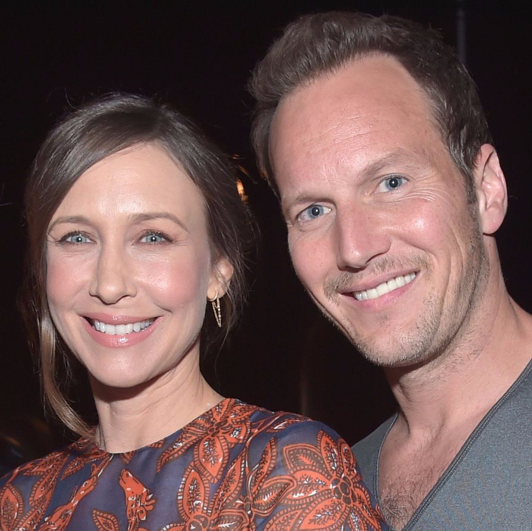 Vera Farmiga smiles with hoop earrings and a floral top with Patrick Wilson.