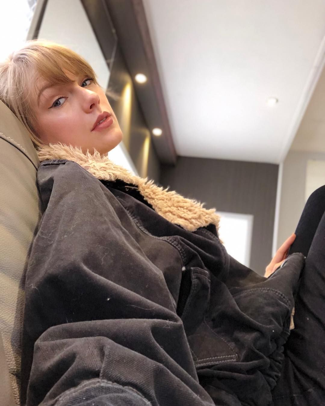 Taylor Swift takes a selfie in an oversized jacket.
