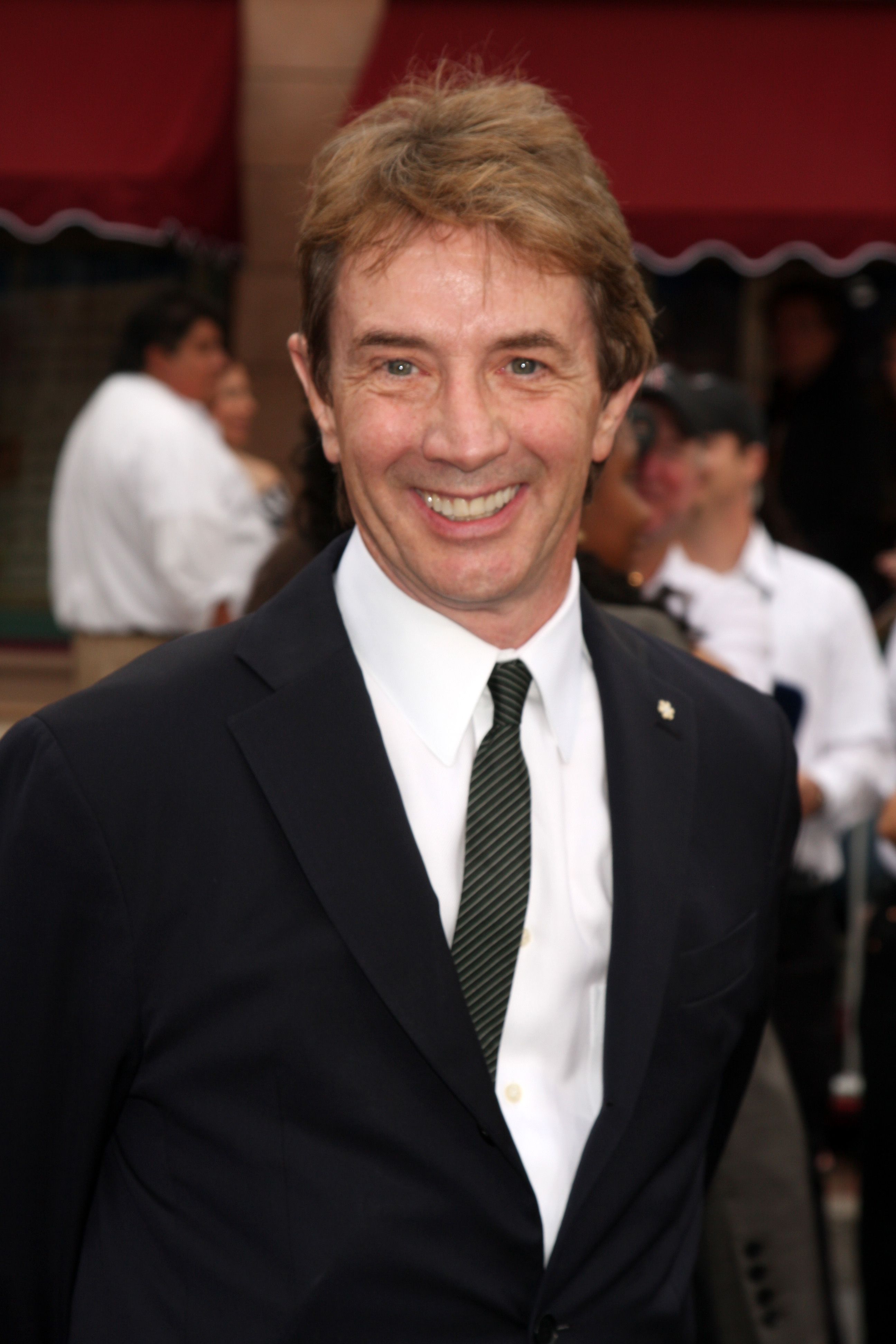 Martin Short smiles in a suit and tie.