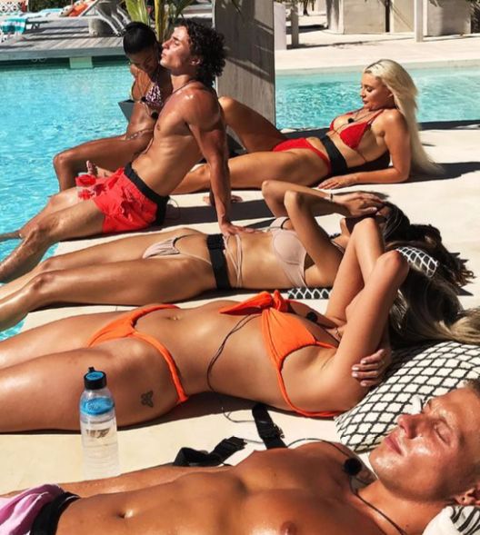 The cast of 'Too Hot to Handle' lays out by a pool.