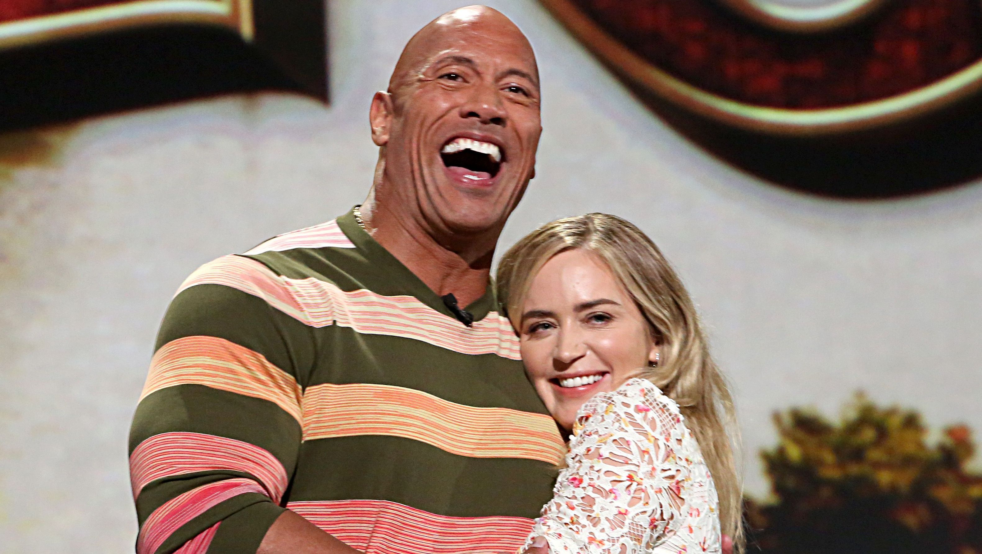 Dwayne 'The Rock' Johnson laughs as Emily Blunt gives him a hug.