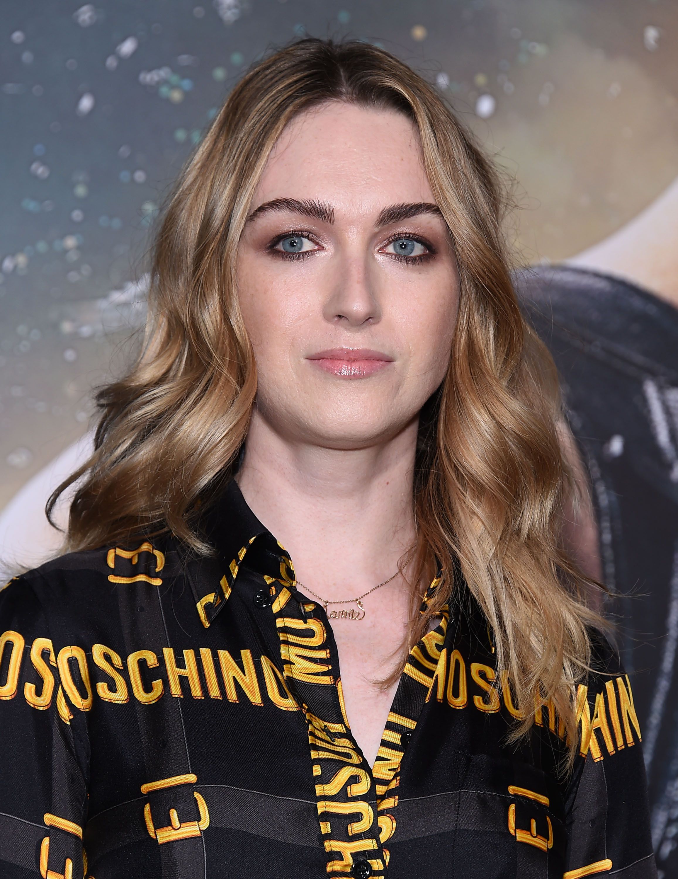 Jamie Clayton wears a black and gold Moschino button-down.