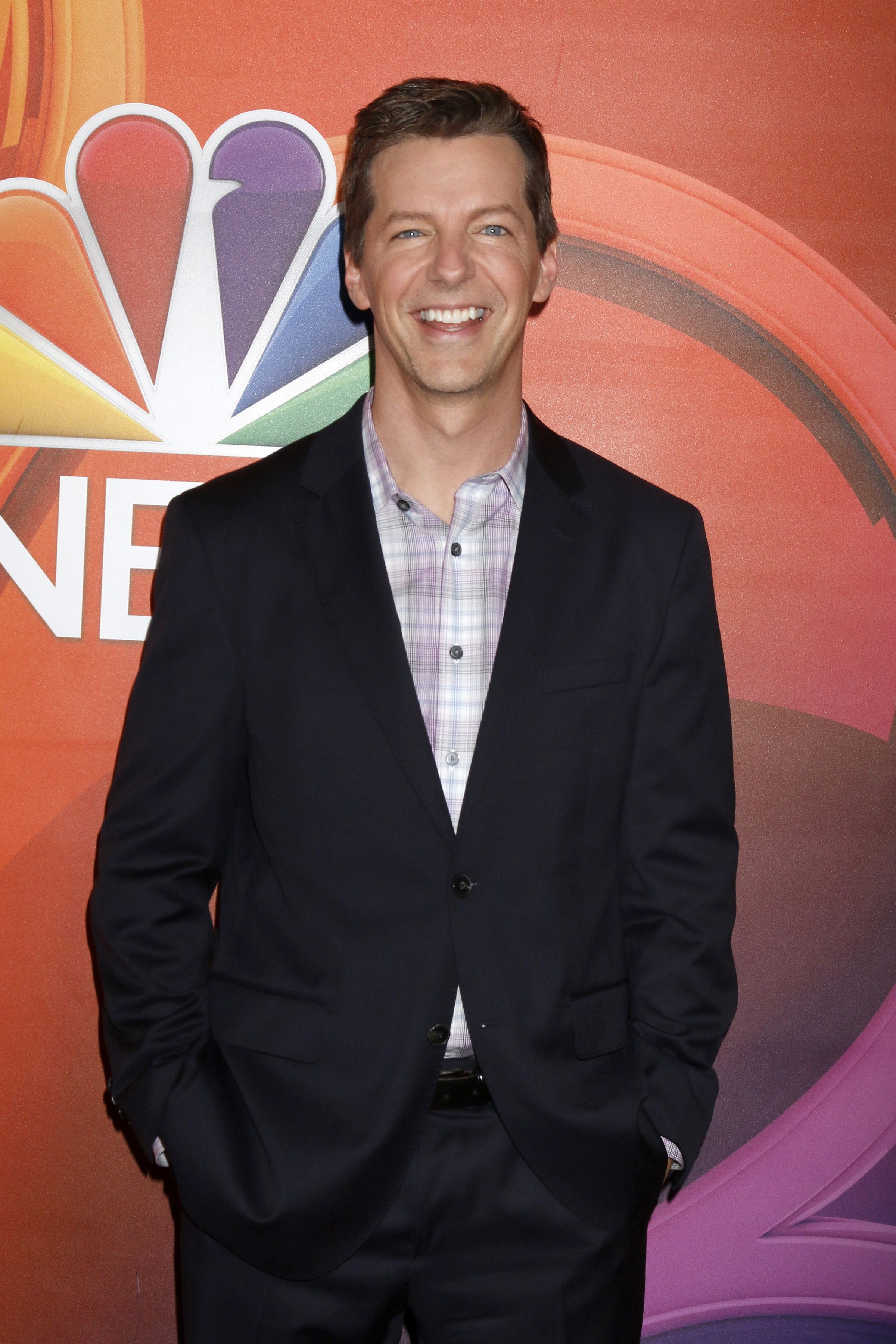 Sean Hayes wears a black suit and plaid shirt.