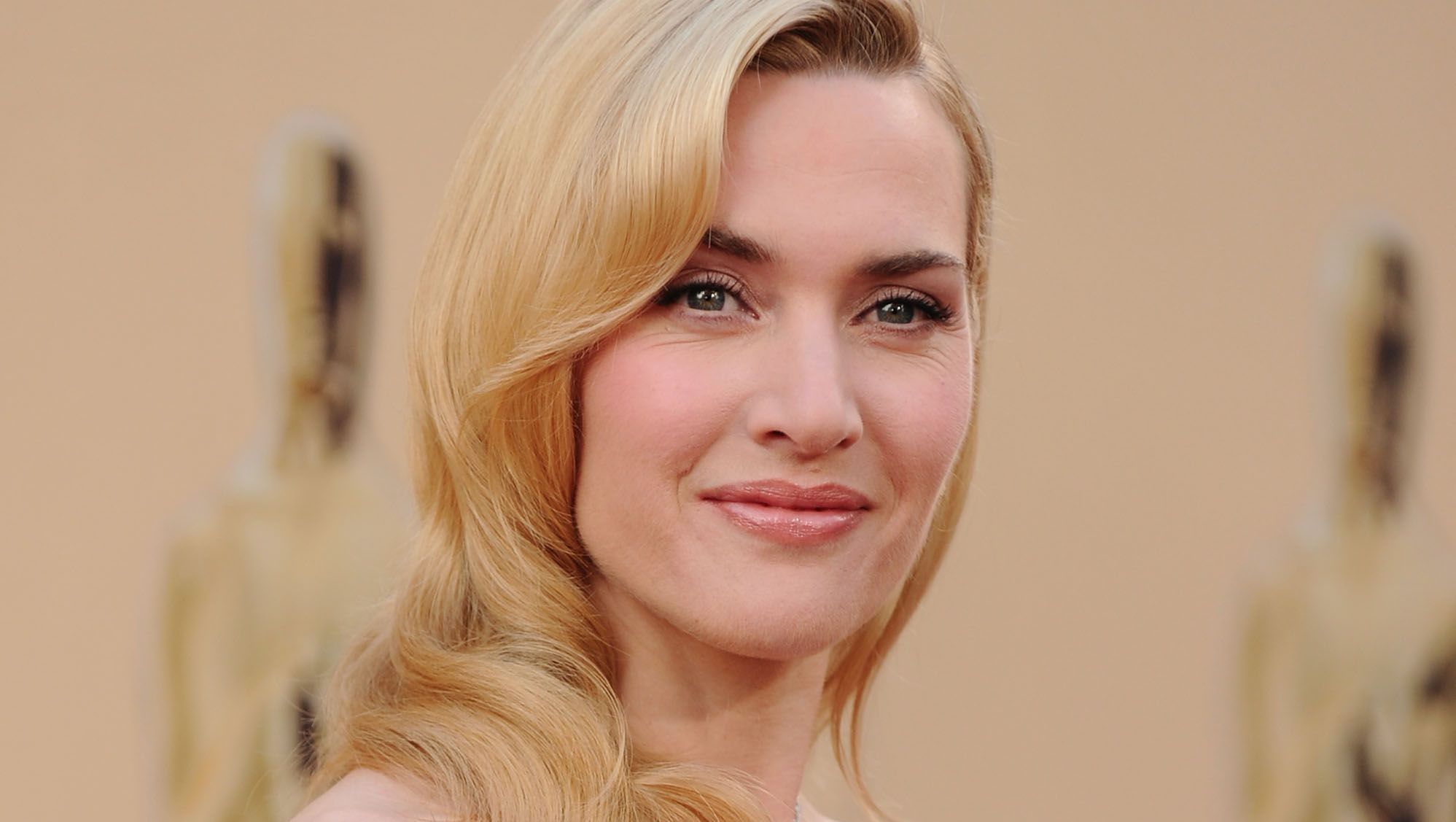 Kate Winslet smiles with her blonde hair curled.