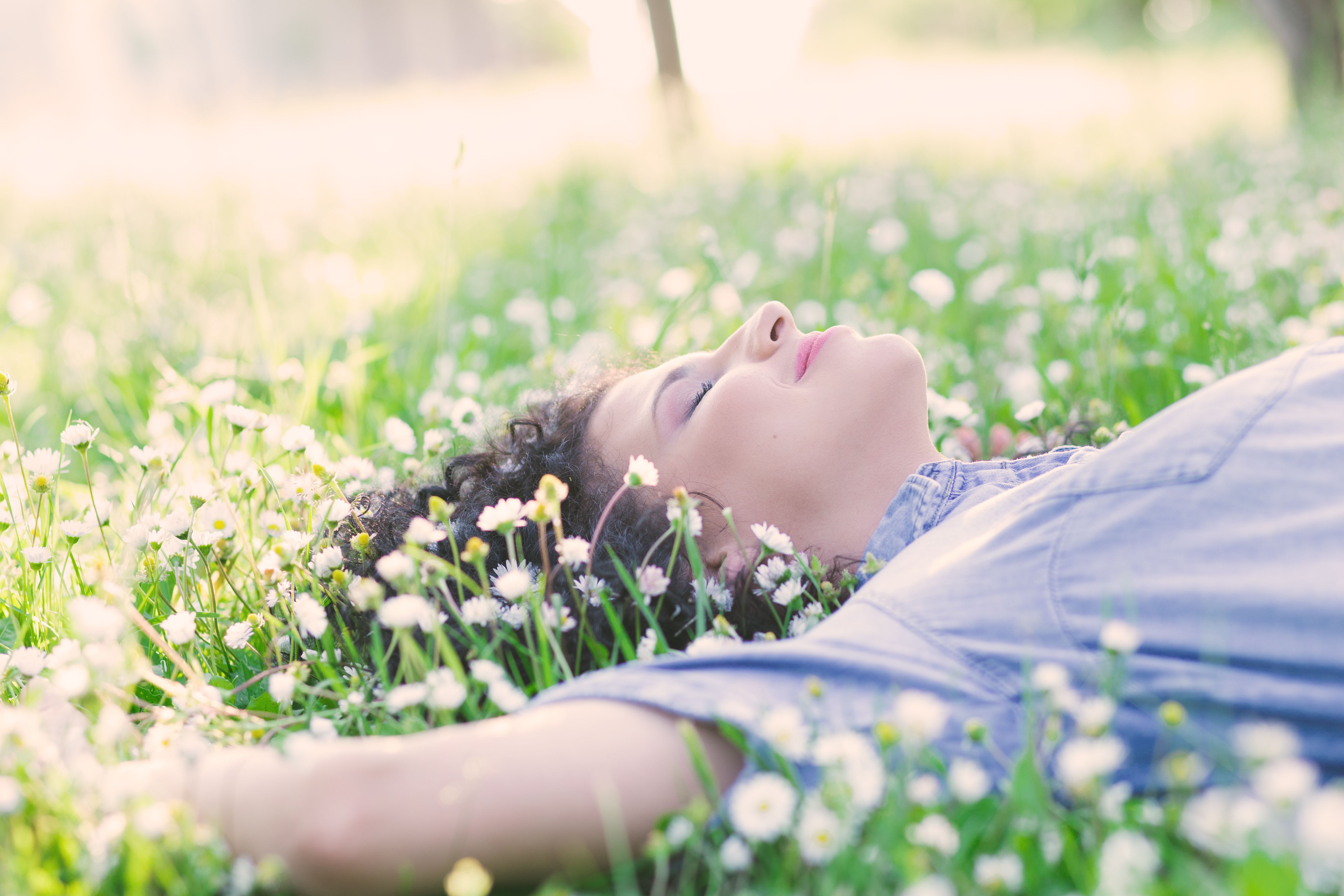 Woman sleeping in a flower-strewn meadow.