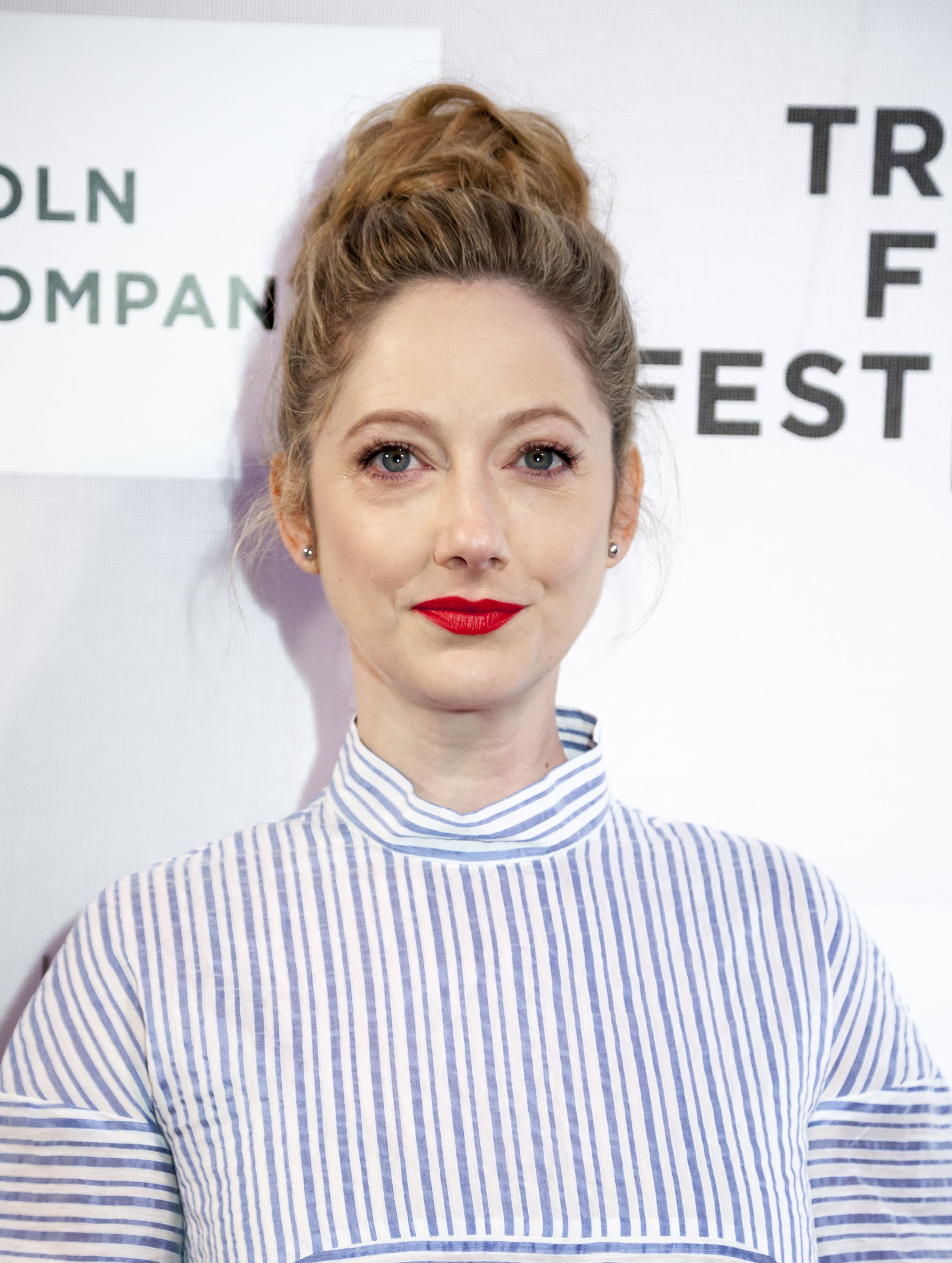 Judy Greer wears red lipstick and a blue and white striped shirt.