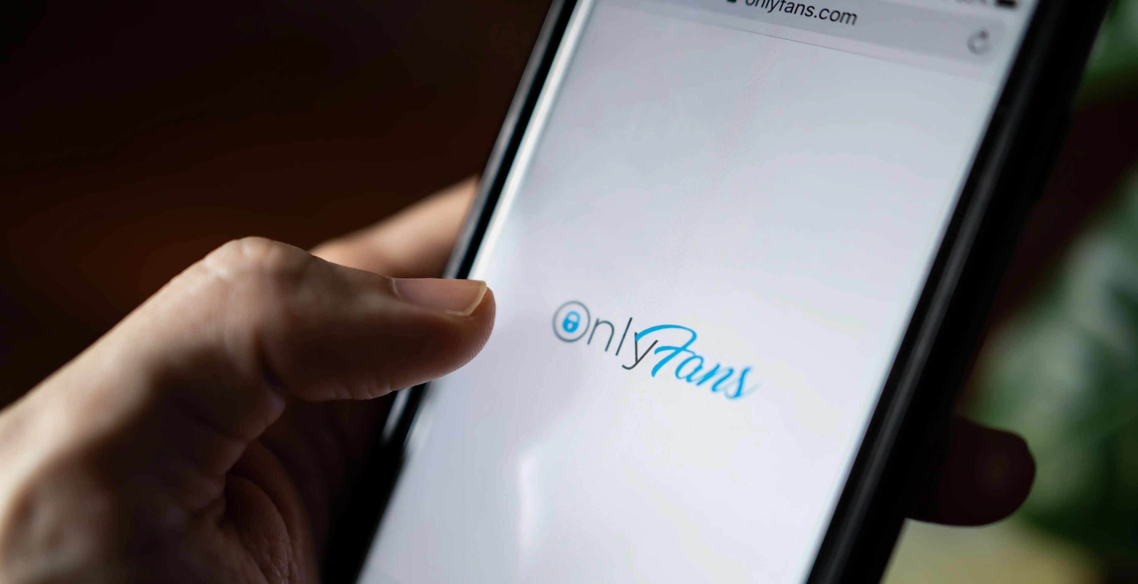 Man browses the OnlyFans website on his phone.
