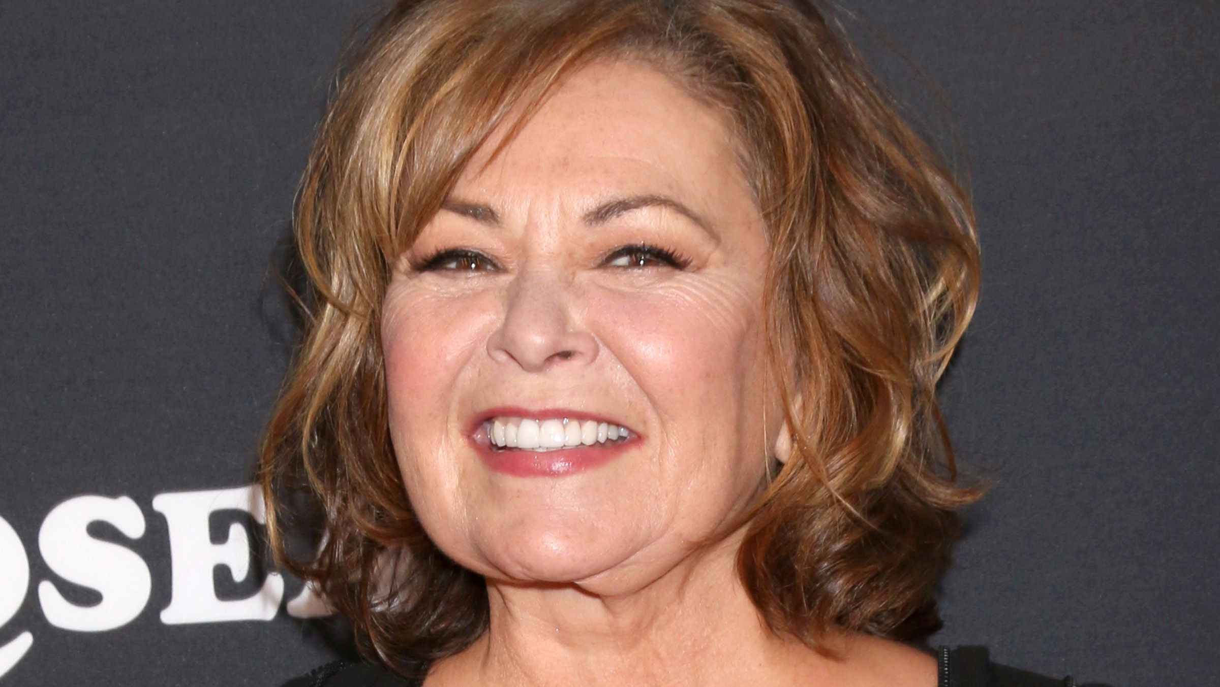 Roseanne Barr smiles with curly hair.