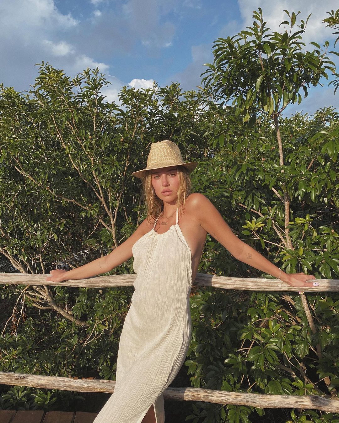 Delilah Hamlin wears a white dress and straw hat.