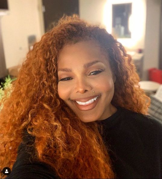 Janet Jackson smiling with curly red hair