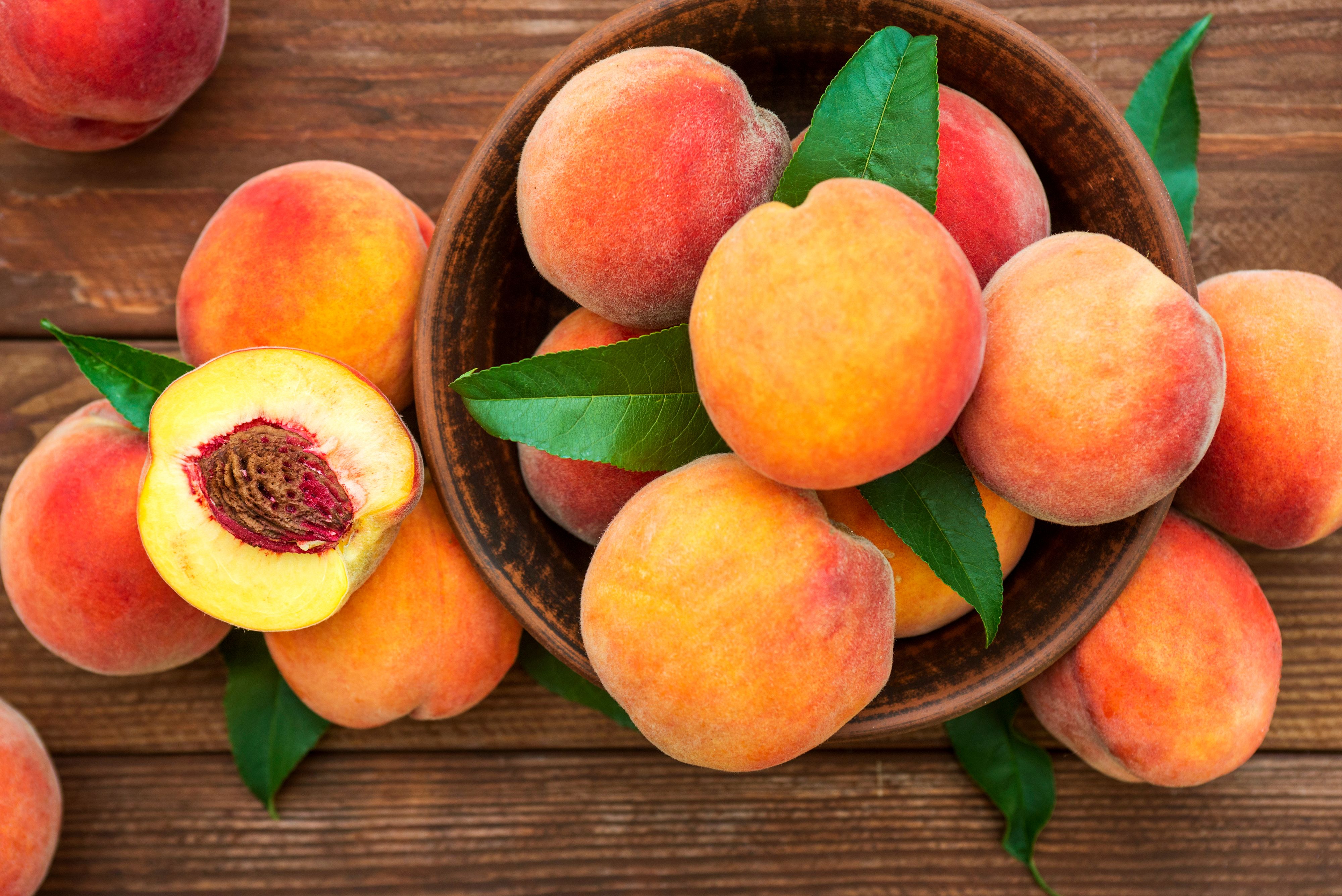 Peaches in a wooden bowl on a table. 