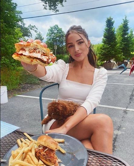 Olivia Culpo outdoors with a sandwich
