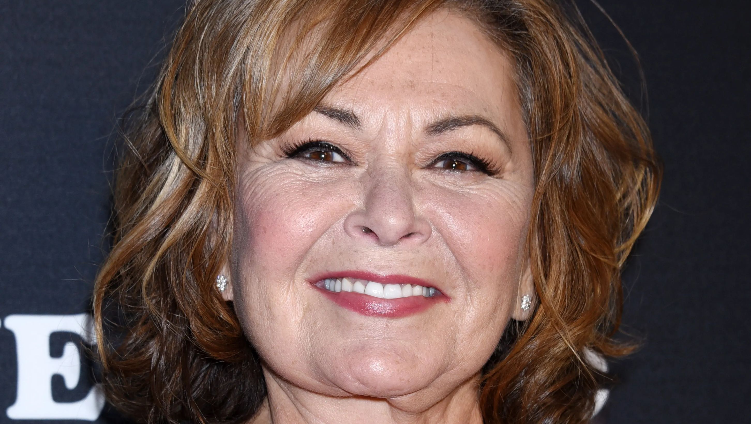 Close-up of Roseanne Barr's face as she smiles on the red carpet at an event. 