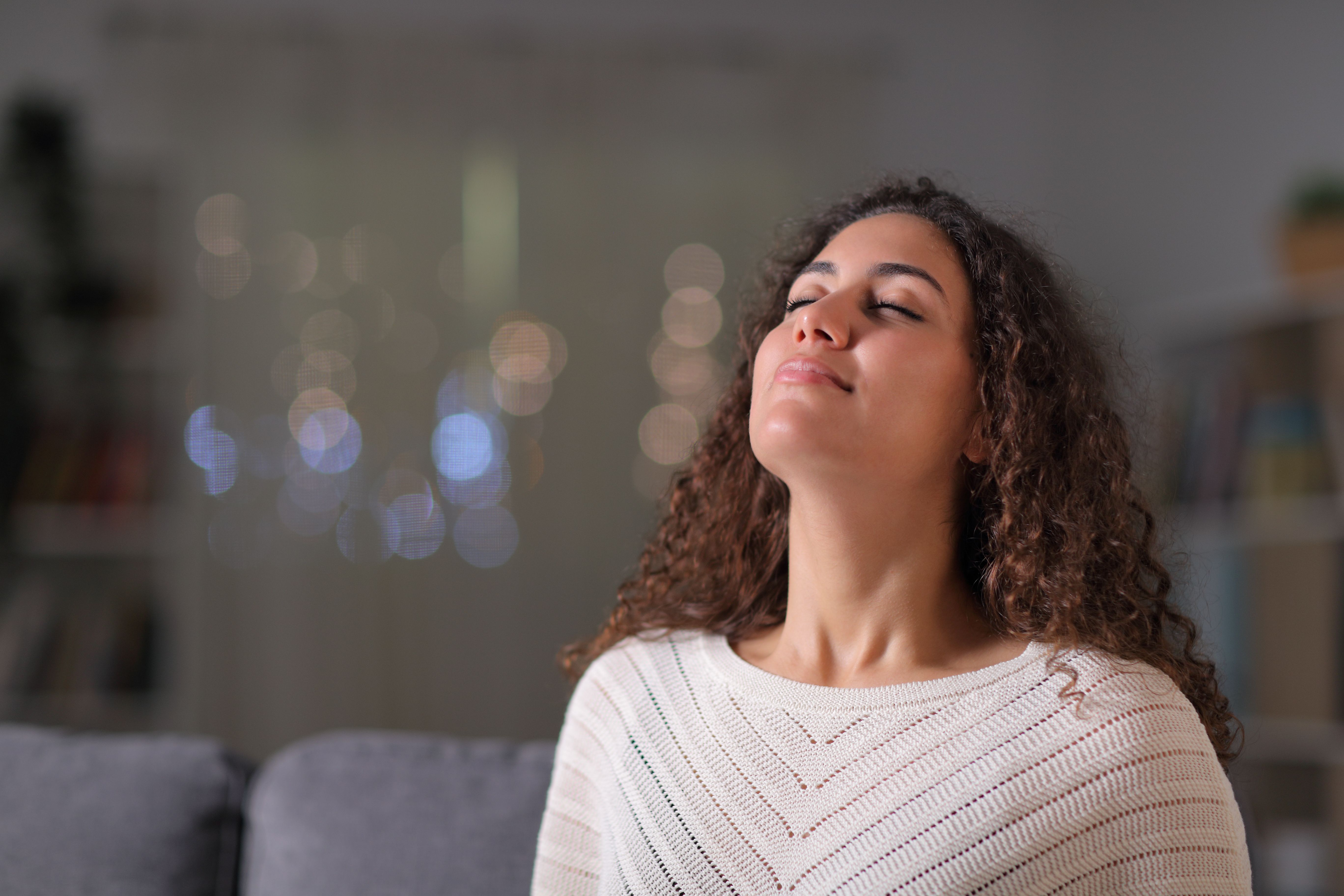 Woman practicing deep breathing on a sofa.