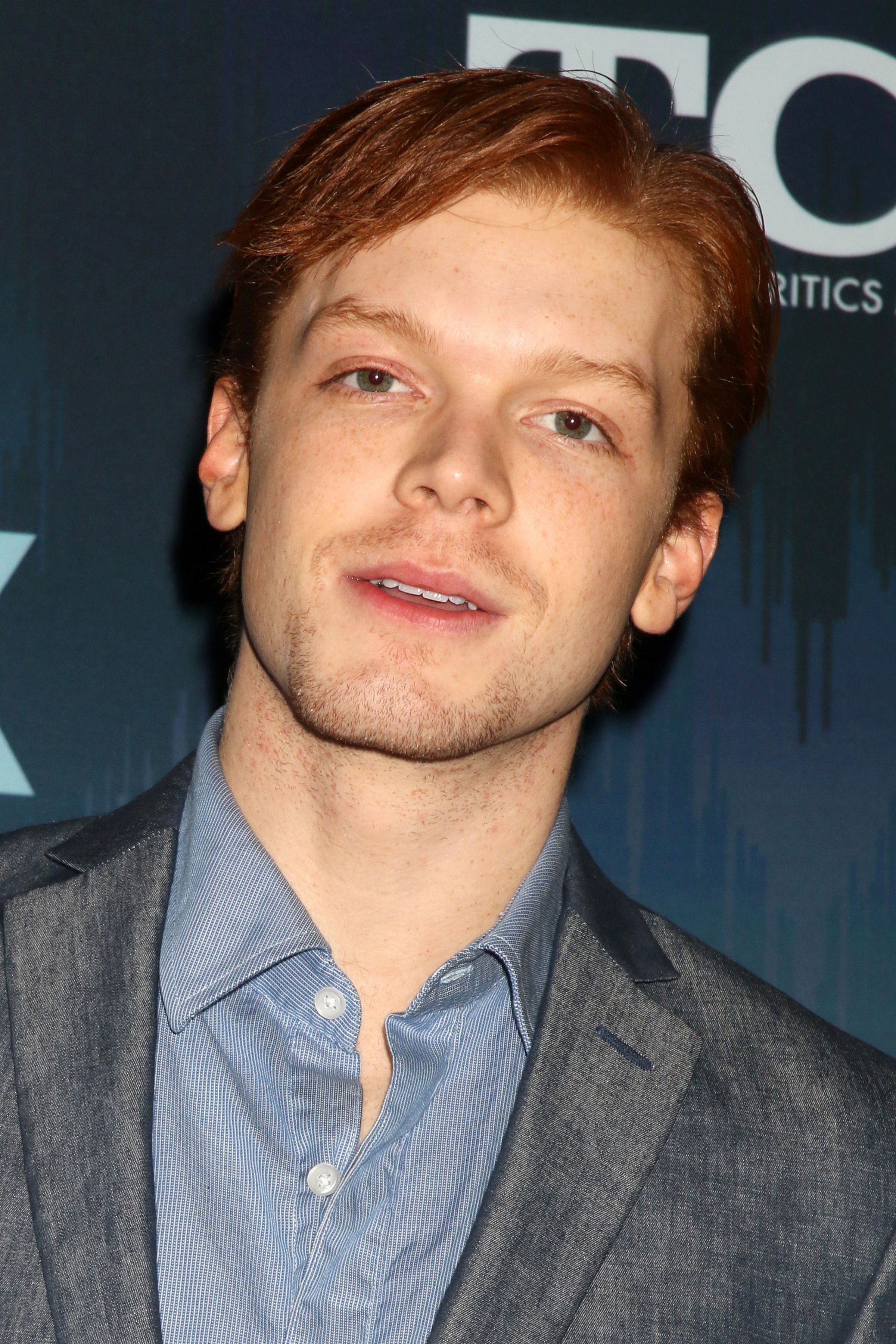 Cameron Monaghan wears a blue button-up and gray blazer.