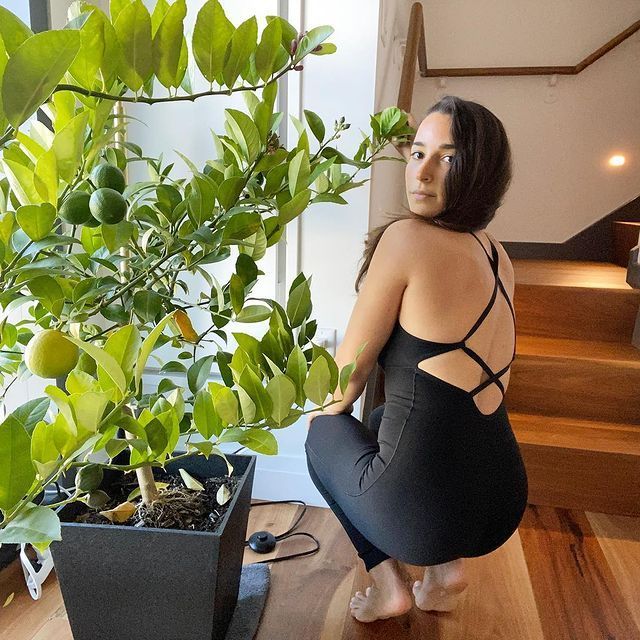 Aly Raisman crouches by plants