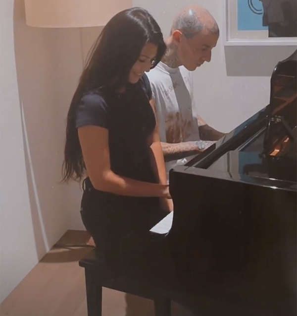 Kourtney Kardashian and Travis Barker play the piano together.