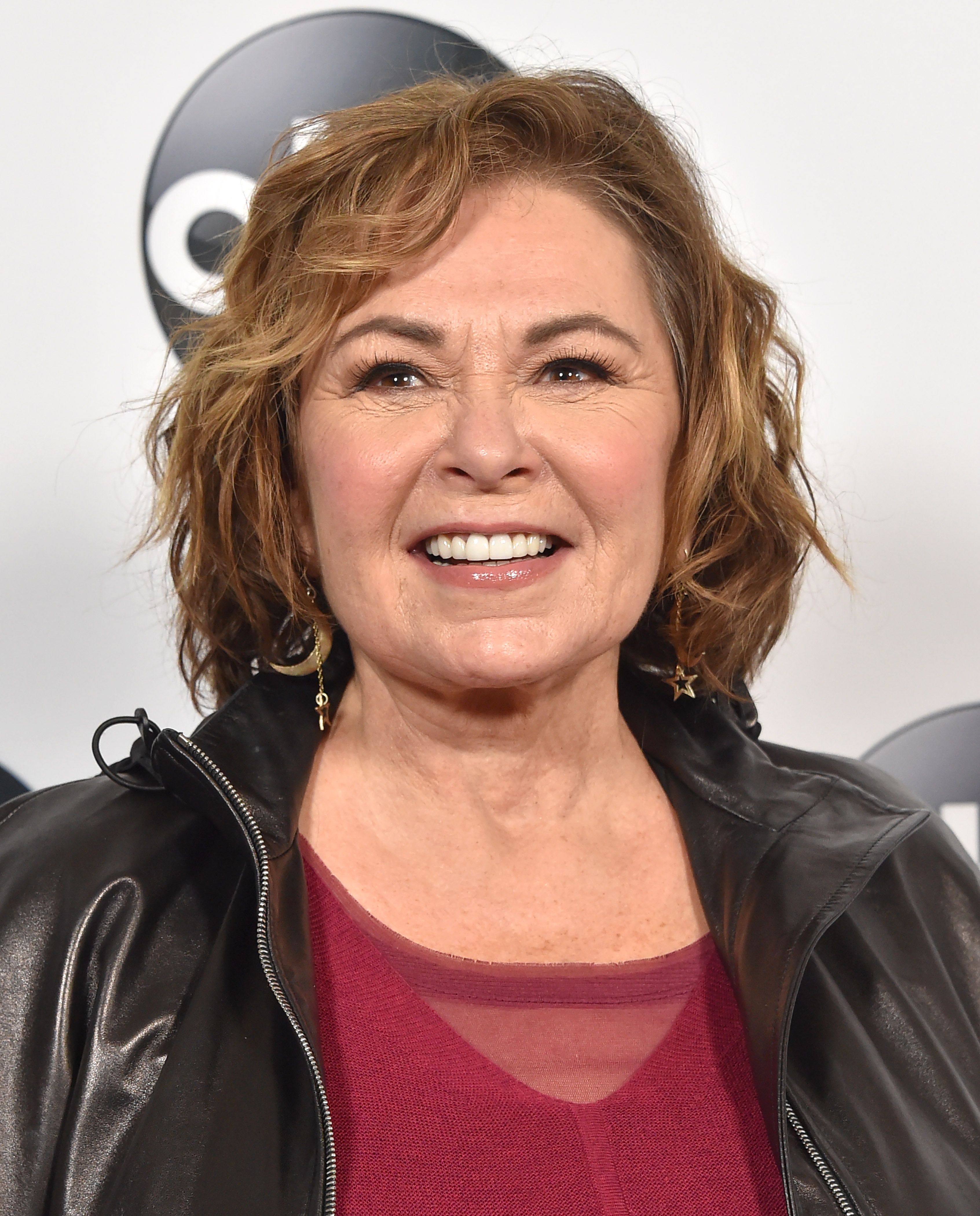 Close-up of Roseanne Barr wearing a red top and black leather jacket. 