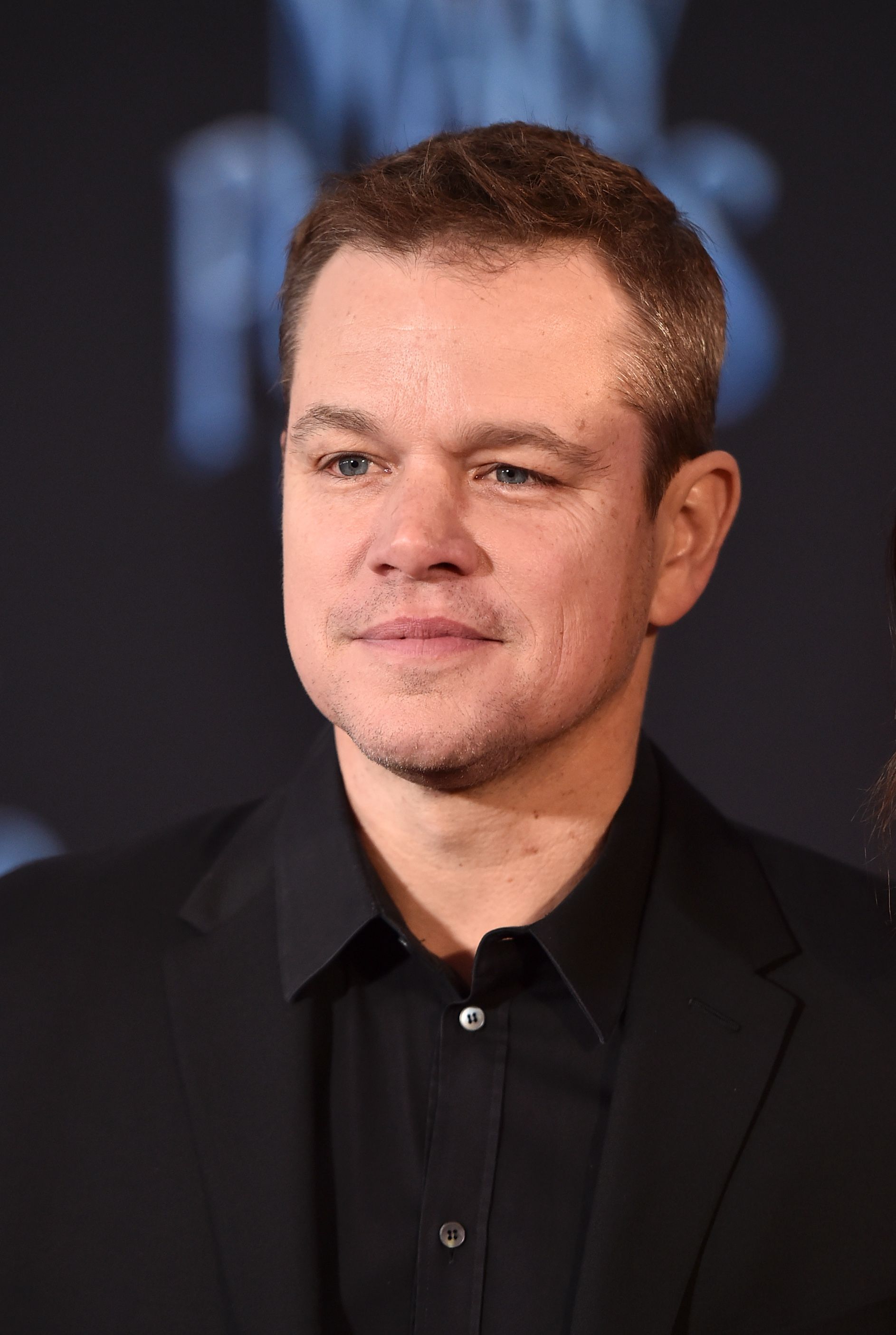 Matt Damon wears a black button up and black blazer.