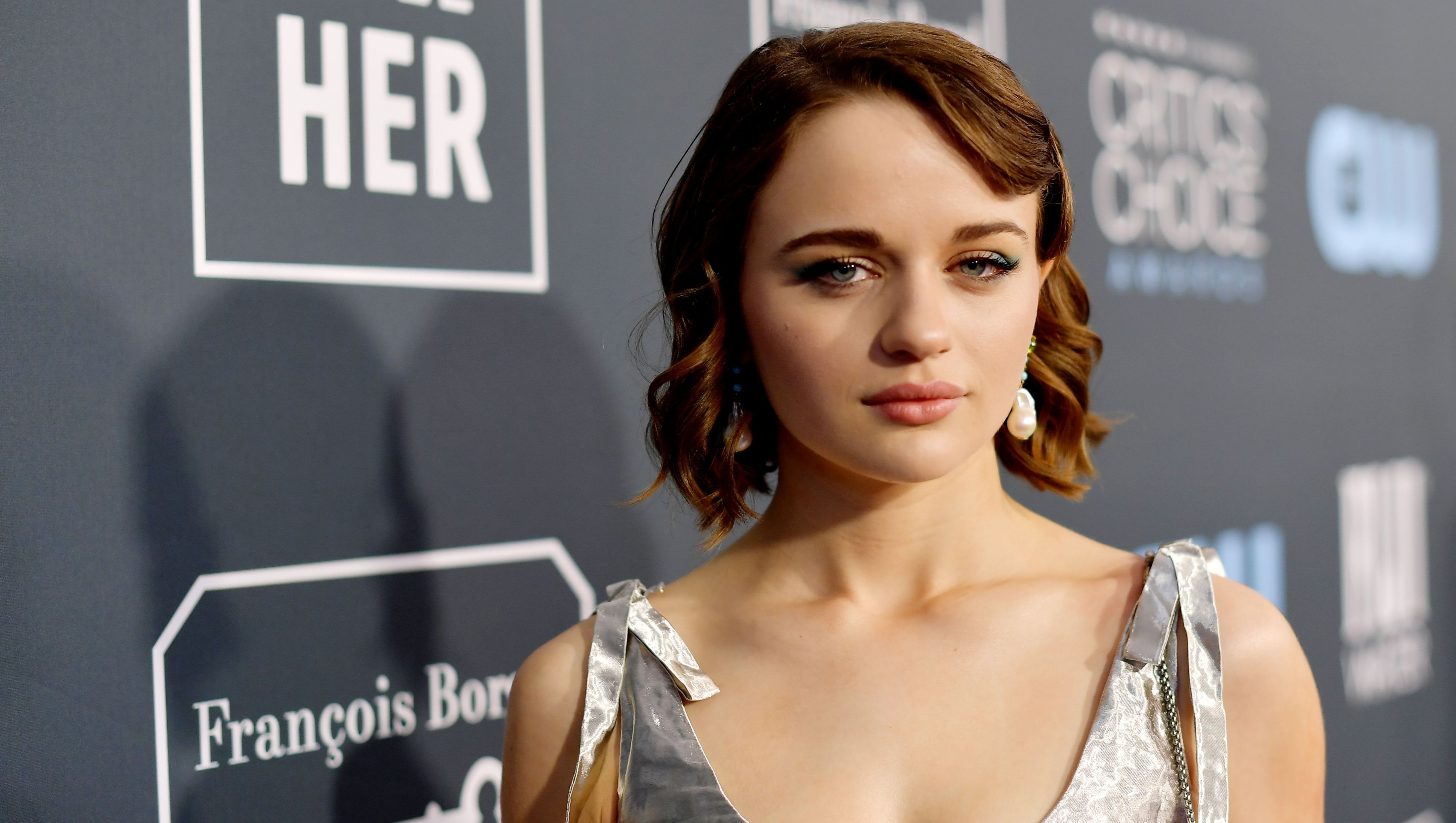 Joey King stares with short hair and a silver dress.