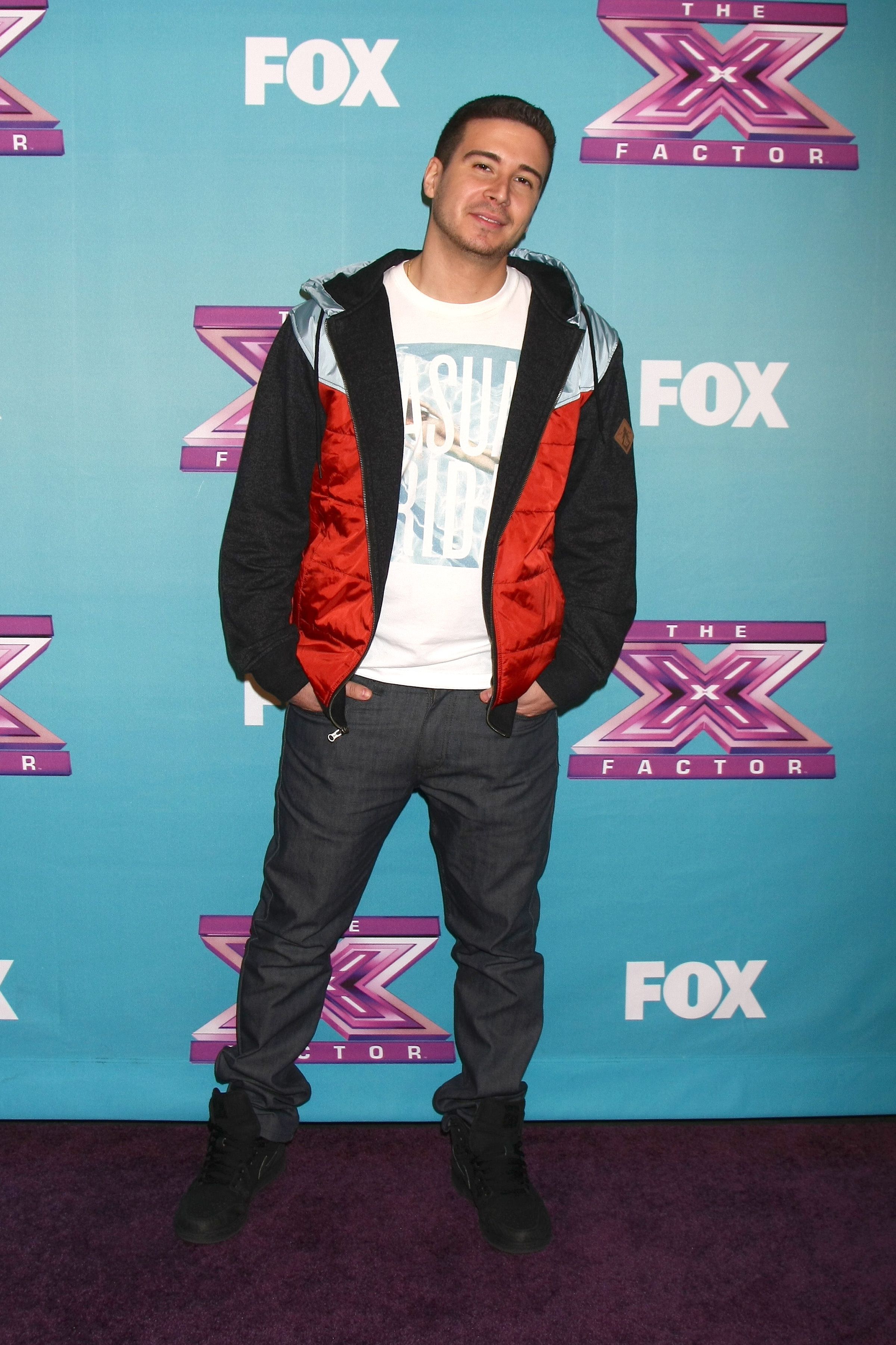 Vinny Guadagnino wears a red, black, and silver jacket over a white T-shirt.