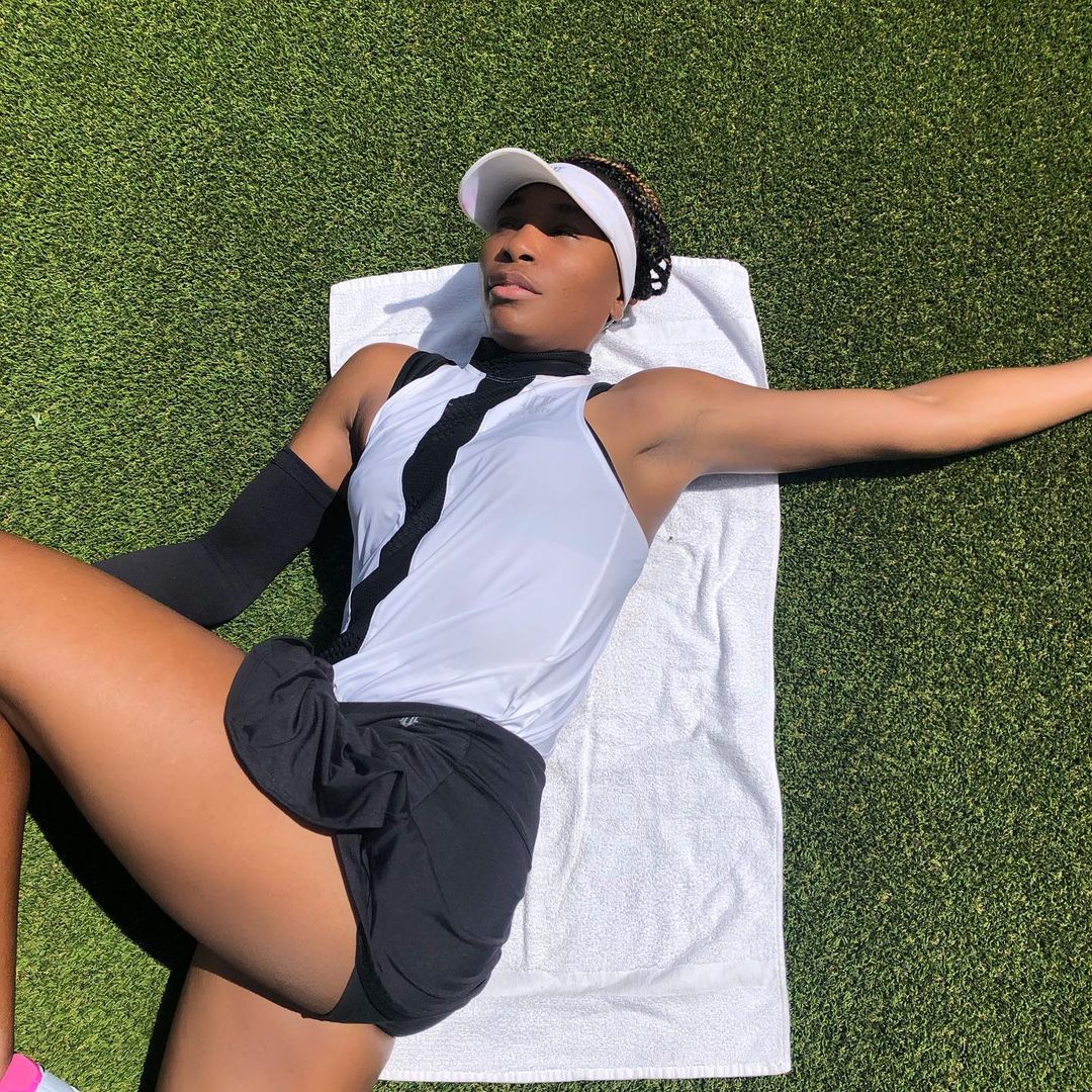 Venus Williams lounges on the court in a clamshell pose. 