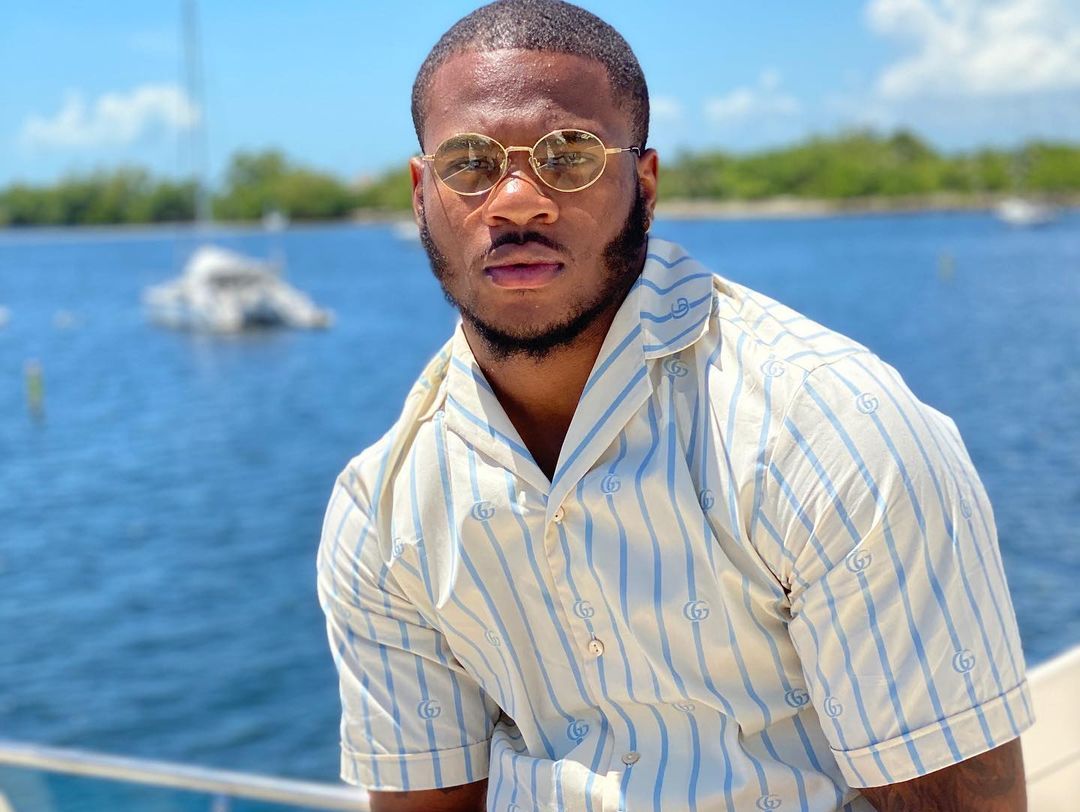 Micah Parsons sitting on a boat in a blue and white striped shirt.