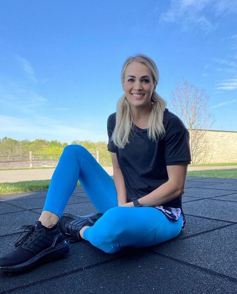 Carrie Underwood poses in blue leggings outdoors